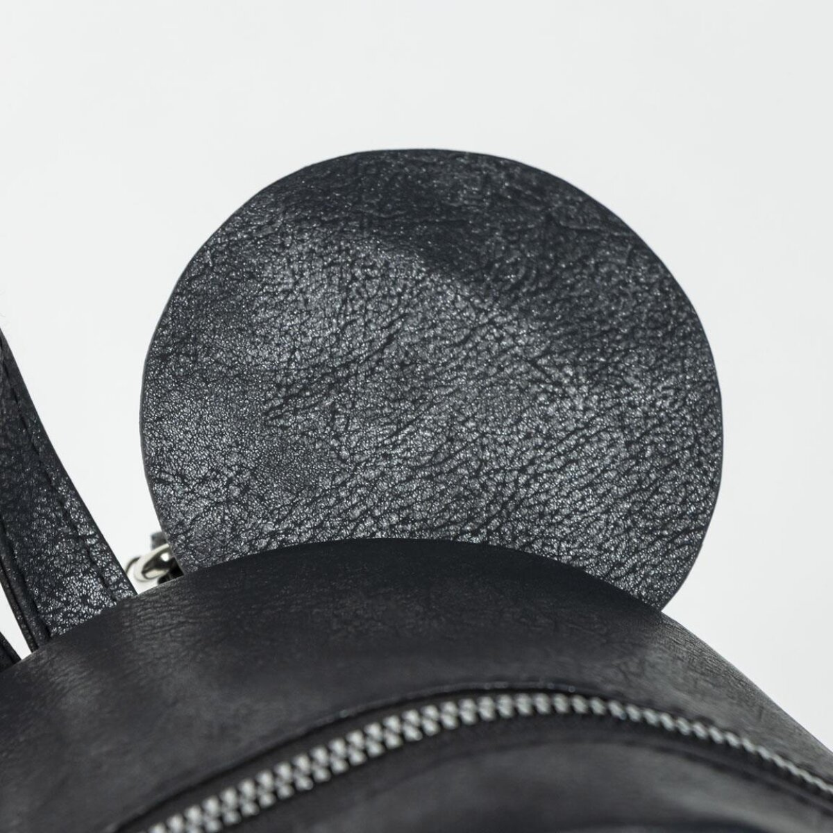 Mochila negra con un diseño circular en forma de oreja en la parte superior.