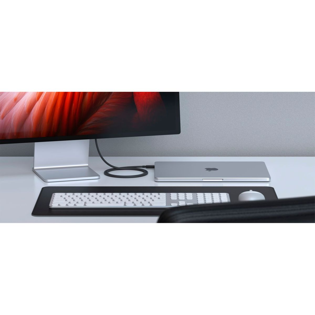 Una configurazione da scrivania pulita con monitor, laptop, tastiera e mouse, tutti ben disposti su un tappetino nero.