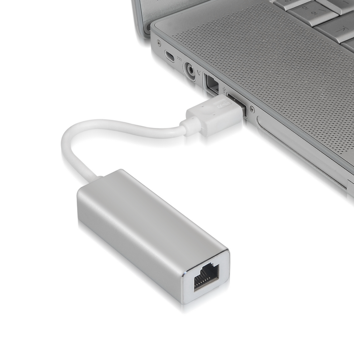 Un adaptador USB a Ethernet plateado conectado a una computadora portátil gris sobre una superficie blanca.