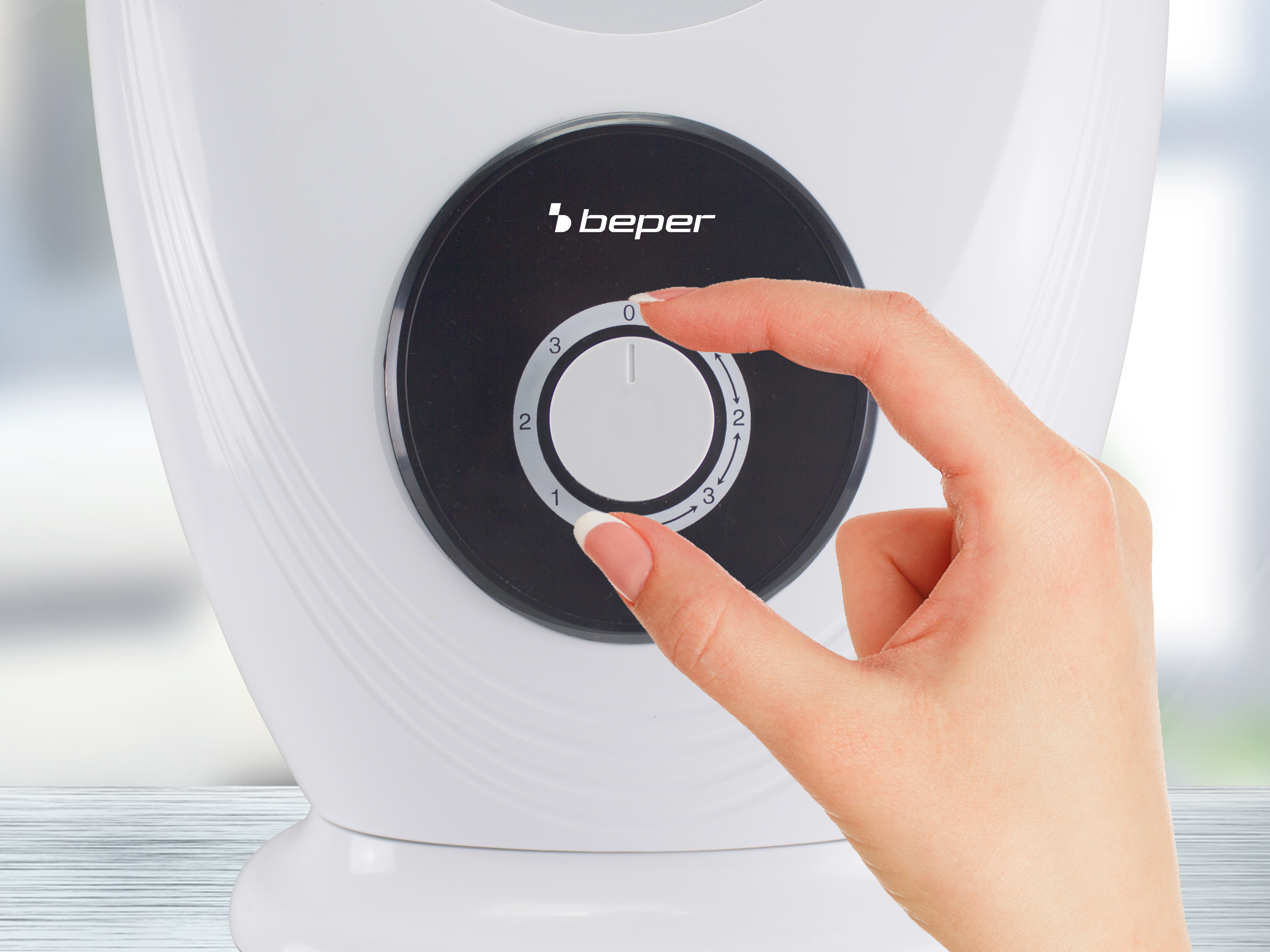 Una mano che gira il quadrante di un ventilatore Beper bianco senza pale, mostrando le impostazioni di velocità.