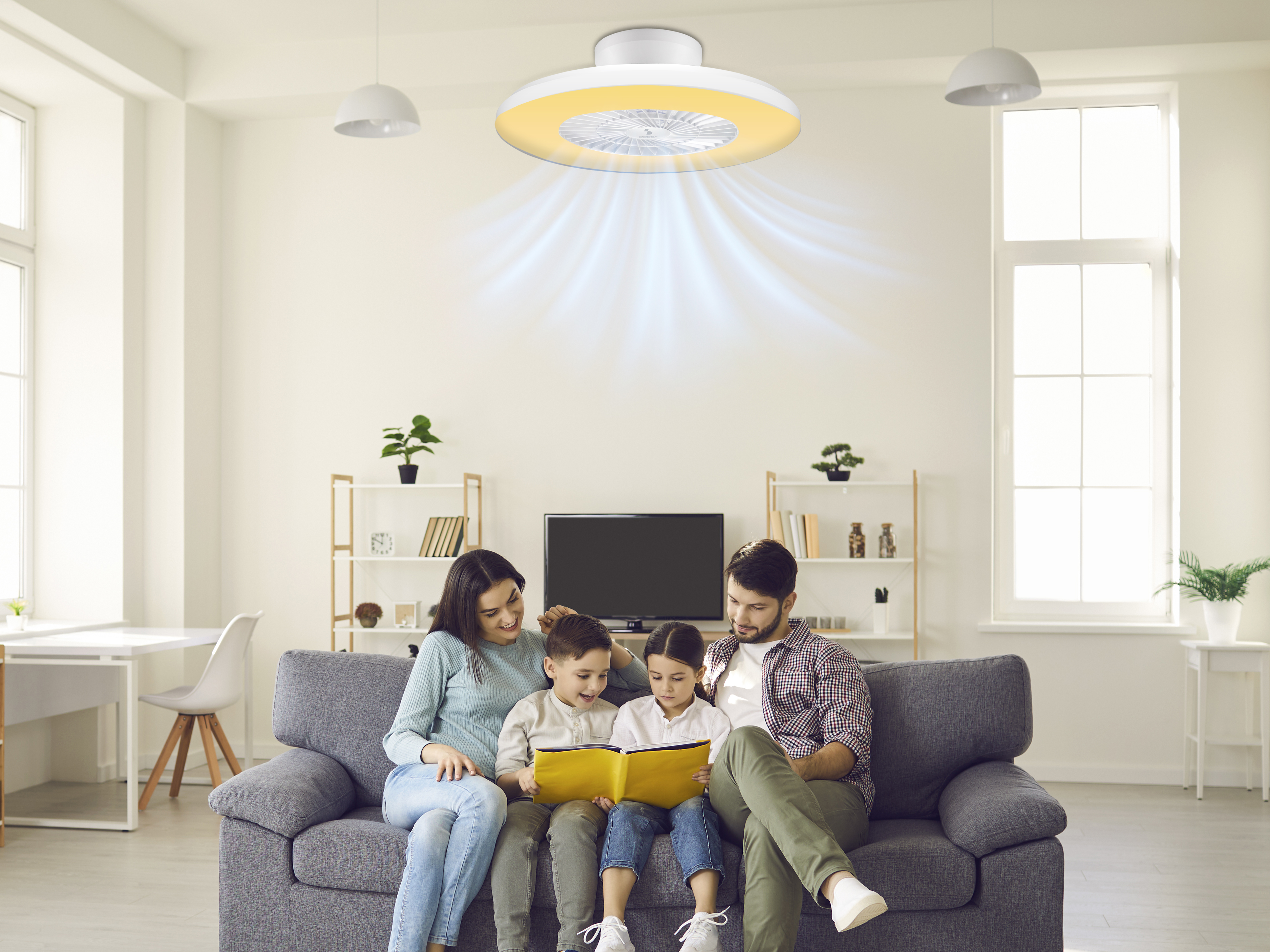 Una famiglia legge un libro sotto un ventilatore a soffitto con illuminazione calda, creando un'atmosfera accogliente nel loro soggiorno.