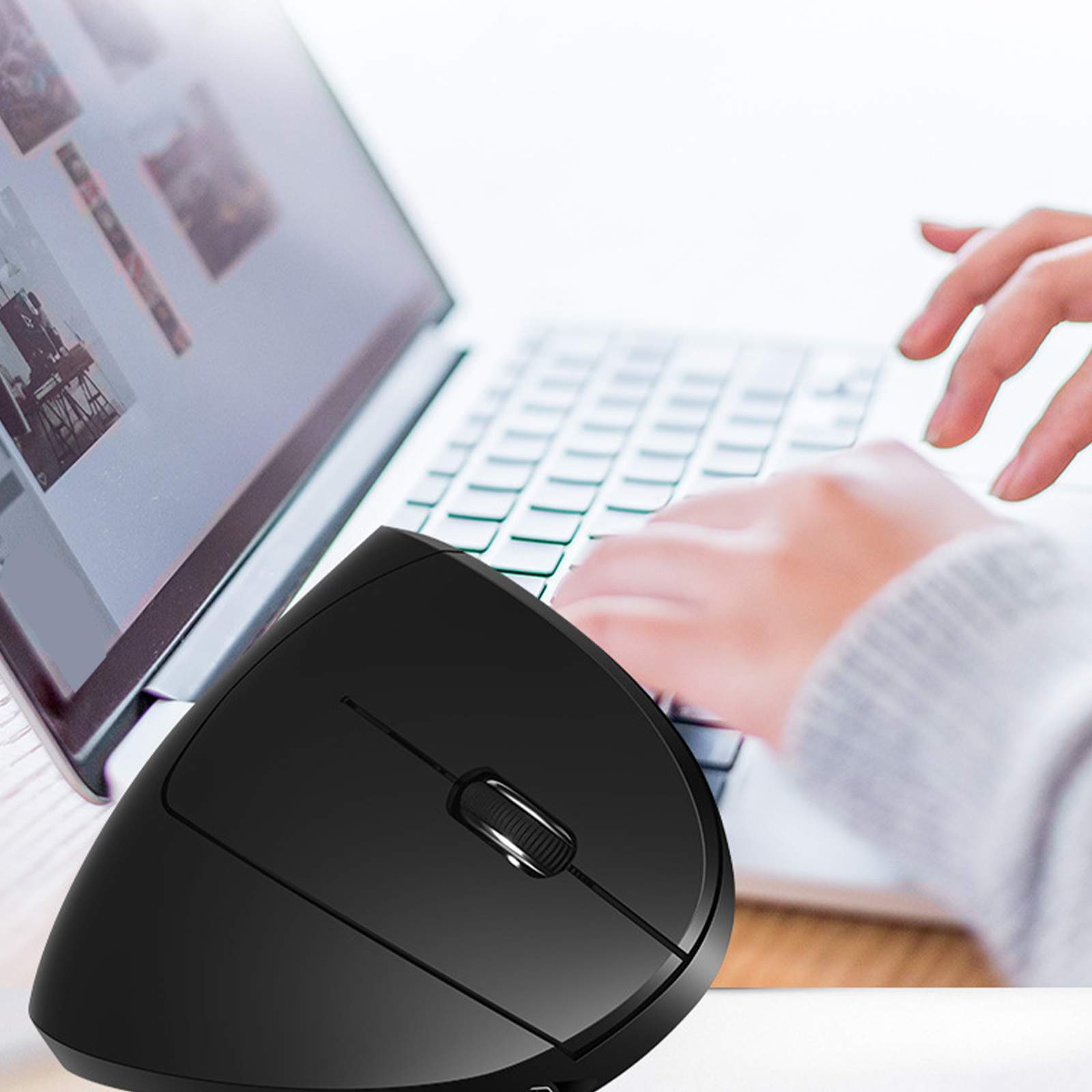 Eine Person, die eine schwarze ergonomische Maus mit einem Laptop benutzt. Die Maus befindet sich rechts.