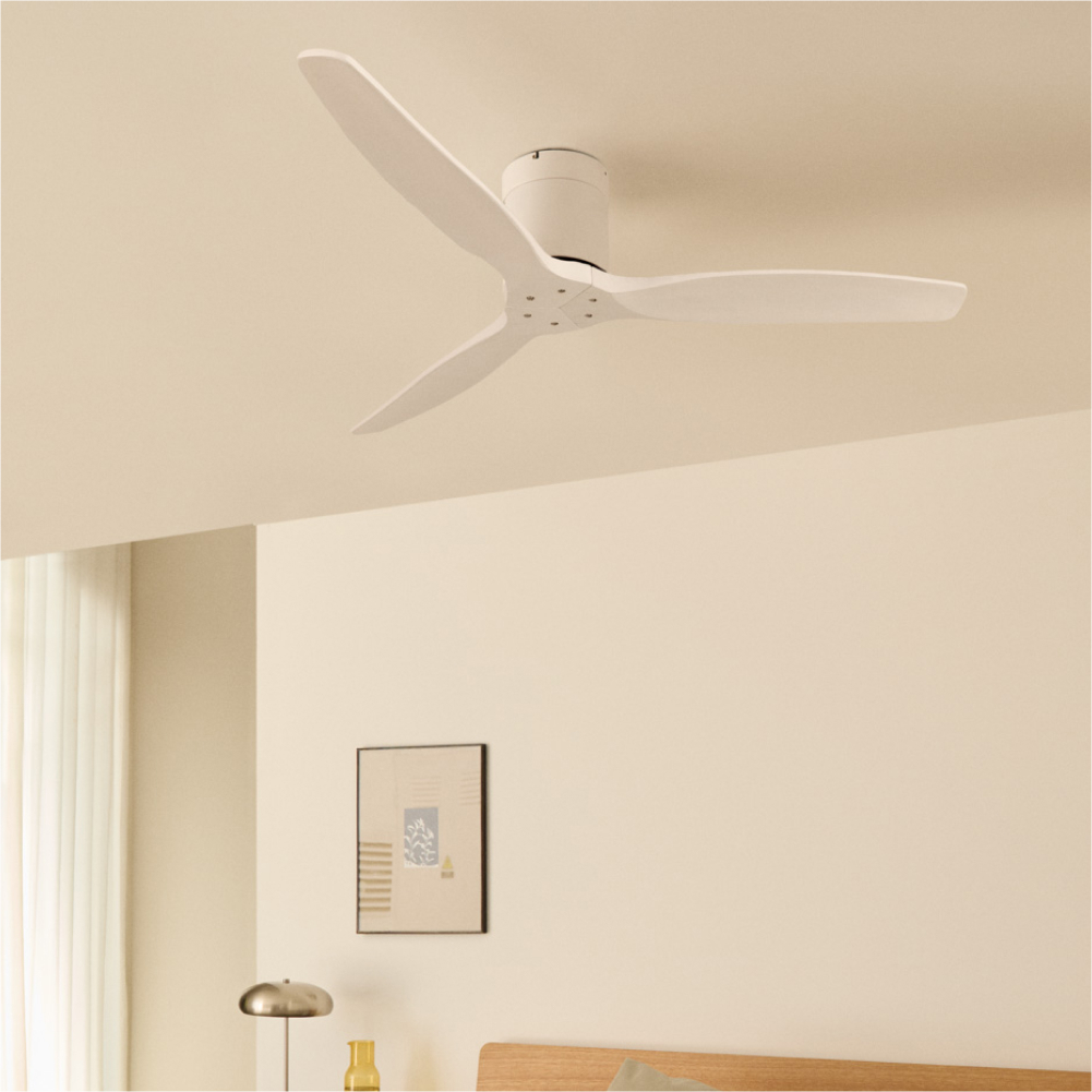 Un ventilador de techo blanco con tres aspas está centrado en la imagen. Una cama y una mesita de noche son visibles.