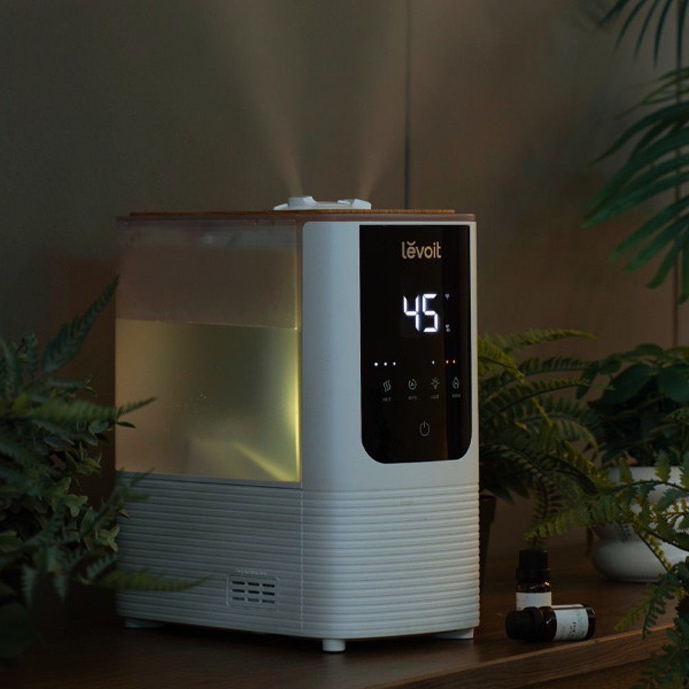 Nawilżacz na drewnianej powierzchni z roślinami, cyfrowy wyświetlacz, olejki eteryczne.