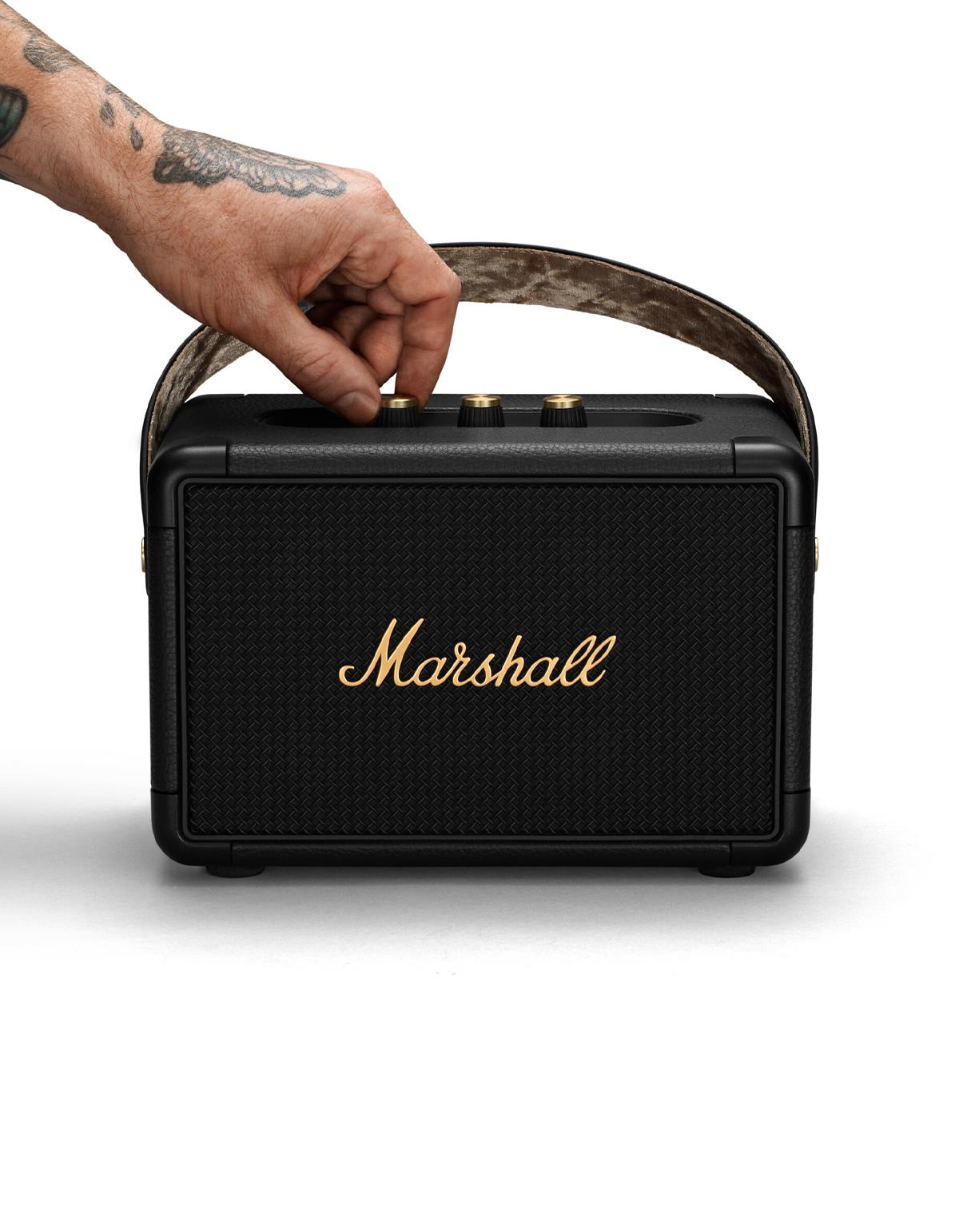 Eine Hand stellt den Lautstärkeregler eines schwarzen Marshall-Lautsprechers ein.