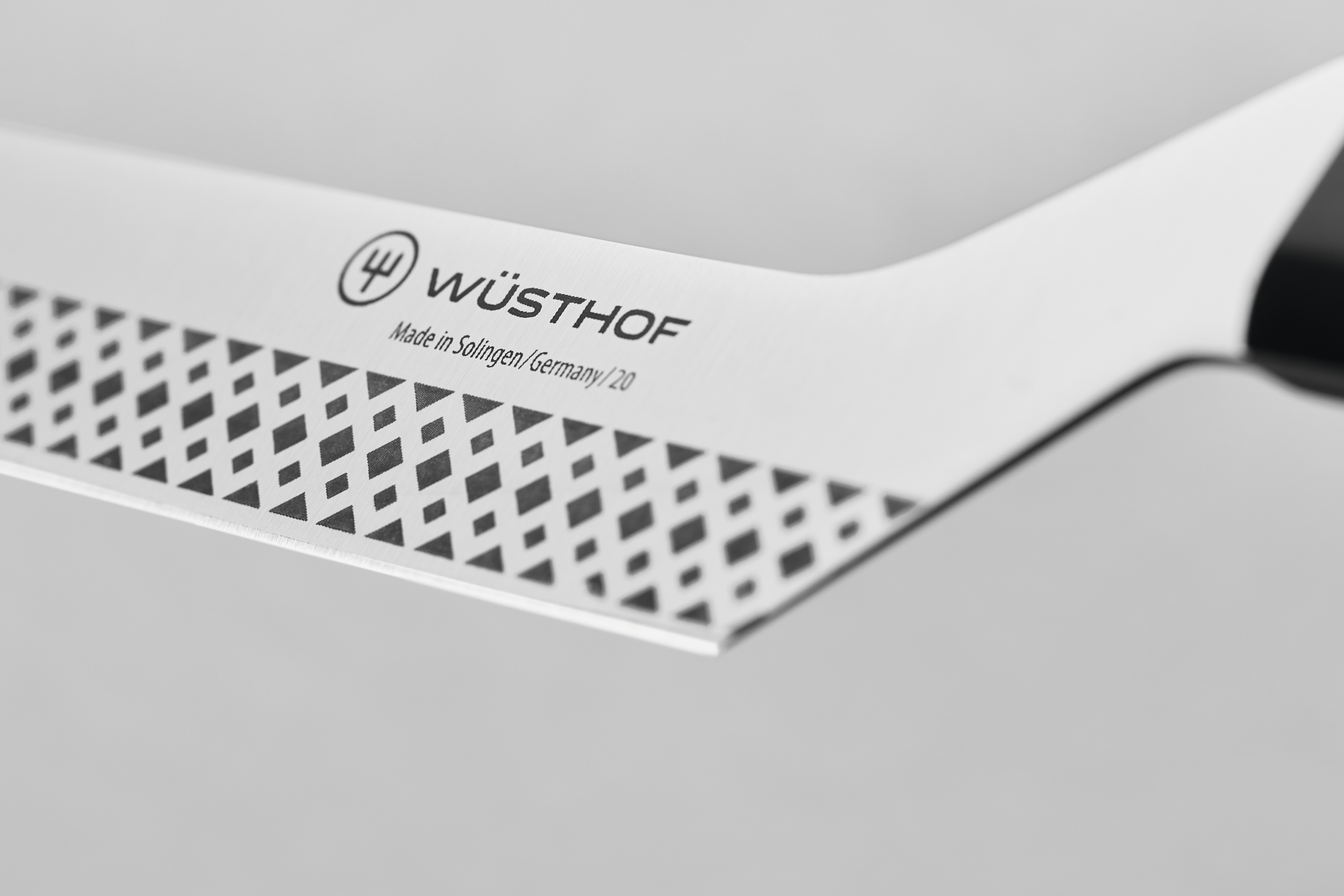 Nahaufnahme einer Käsemesserklinge mit Musterdesign und dem Wüsthof-Logo auf weißem Hintergrund.
