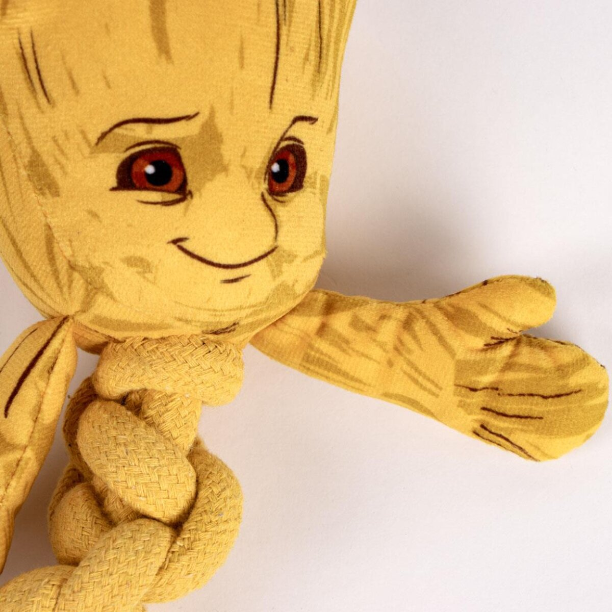 Un peluche di Baby Groot con un braccio teso e una corda gialla annodata sotto.