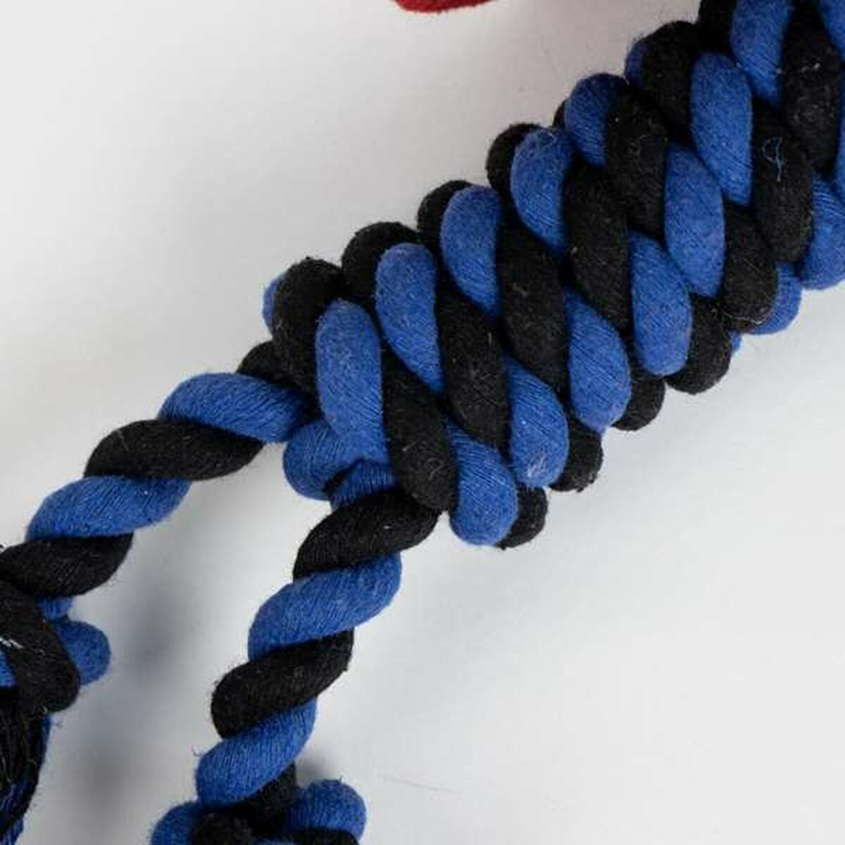 Nahaufnahme eines Hundespielzeugs aus verflochtenem blauem und schwarzem Seil.
