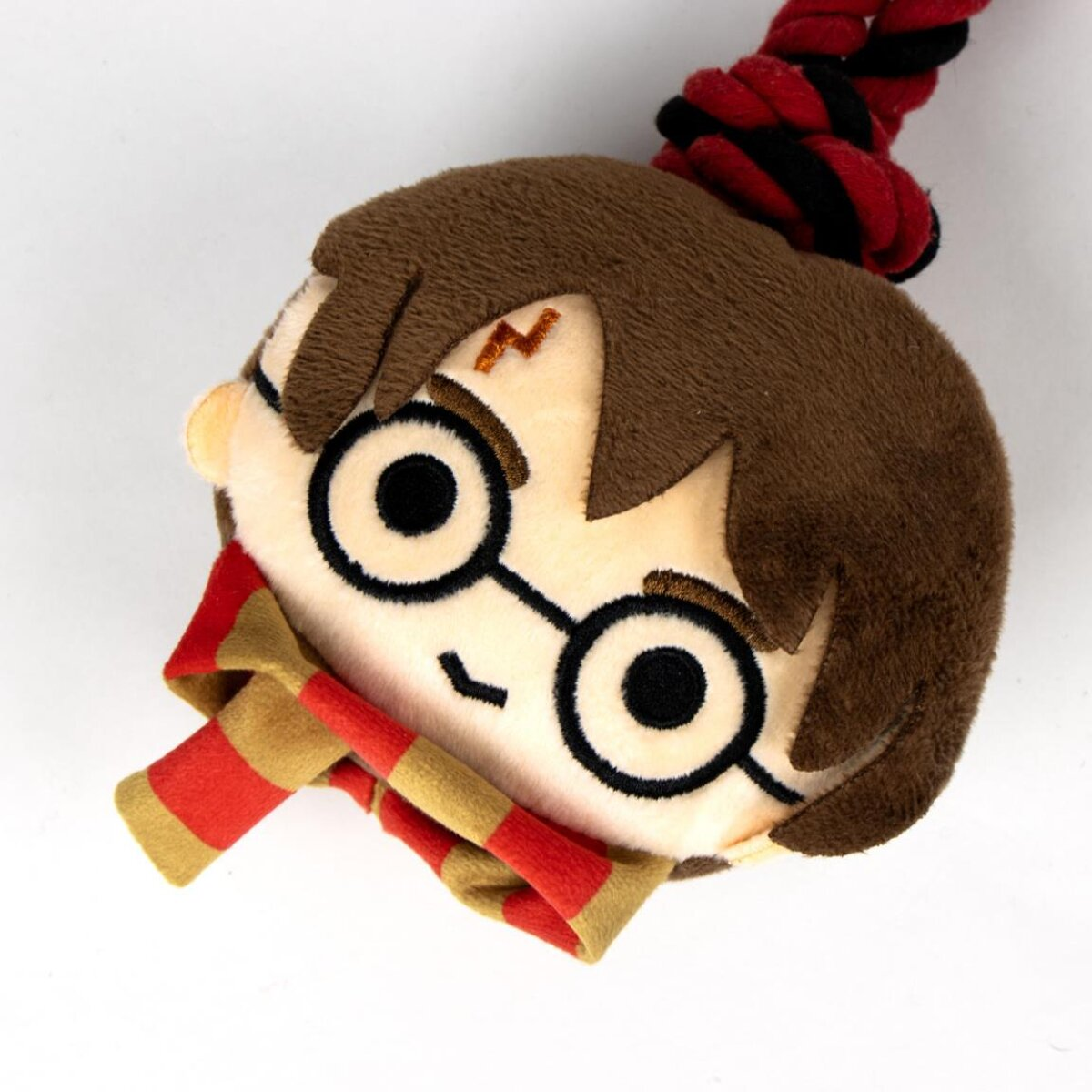 Harry Potter Plüschtier mit Schal, Brille und Blitznarbe. Das Spielzeug liegt auf Weiß.