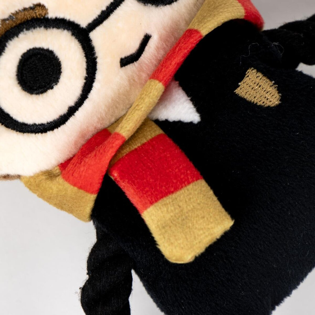 Nahaufnahme einer Harry Potter Plüschpuppe, mit Brille, Schal und geflochtener Frisur.