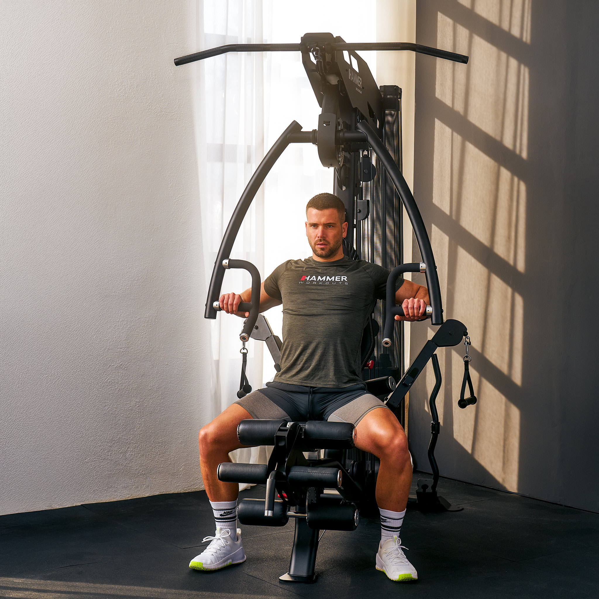 Ein Mann in grauem Hemd trainiert an einer schwarzen Hammer Heimtrainingsmaschine.