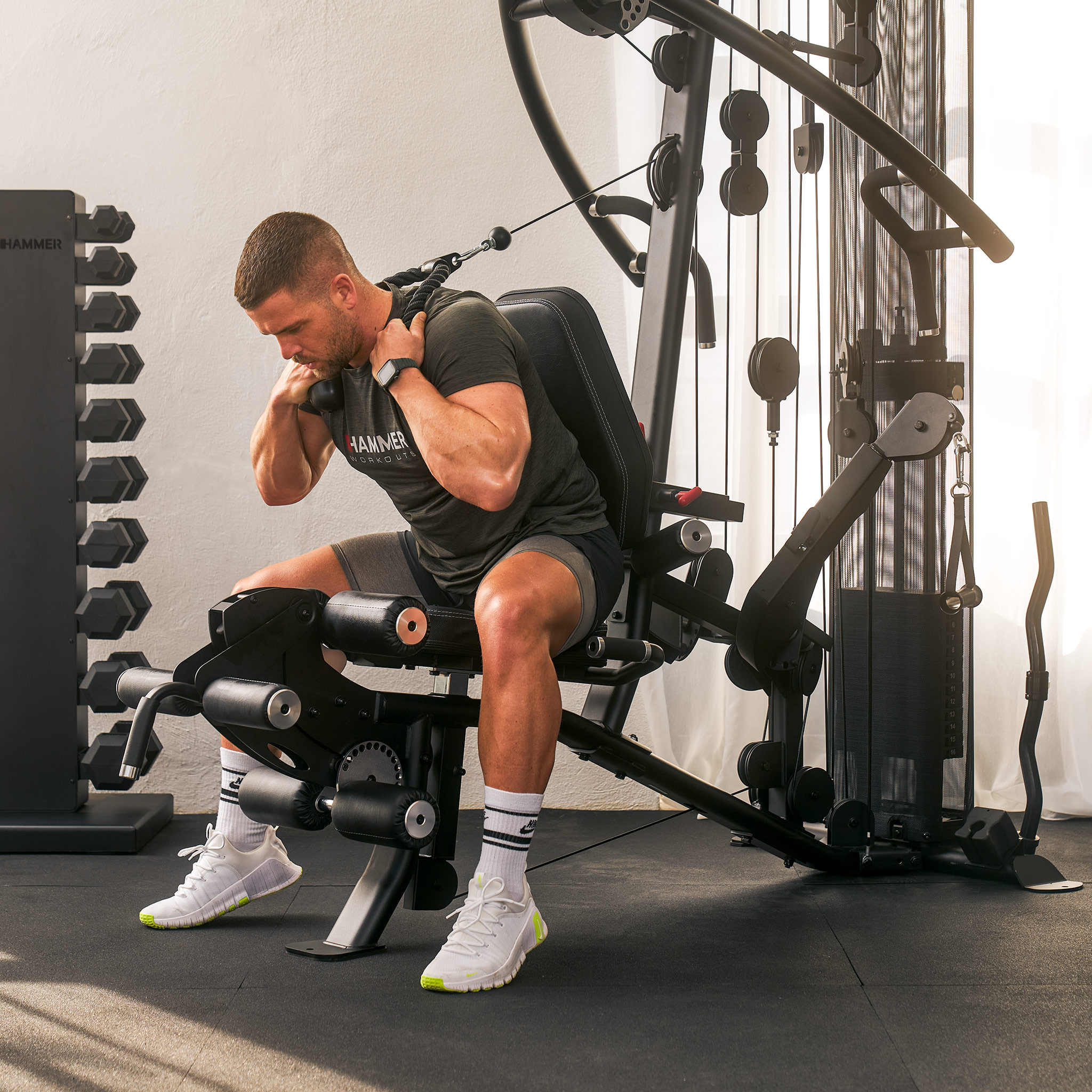 Ein Mann trainiert an einer Multi-Gym-Maschine und führt eine Ruderübung im Sitzen aus.
