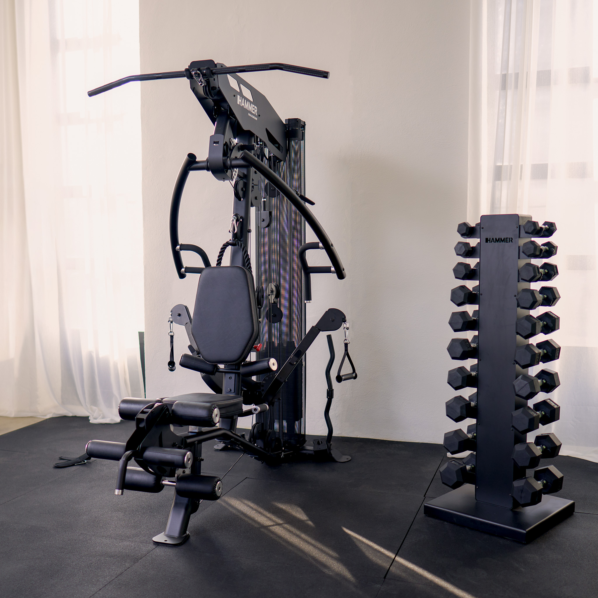 Ein Home Gym mit einer Mehrstationen-Maschine, Kurzhanteln und einem schwarzen Boden.
