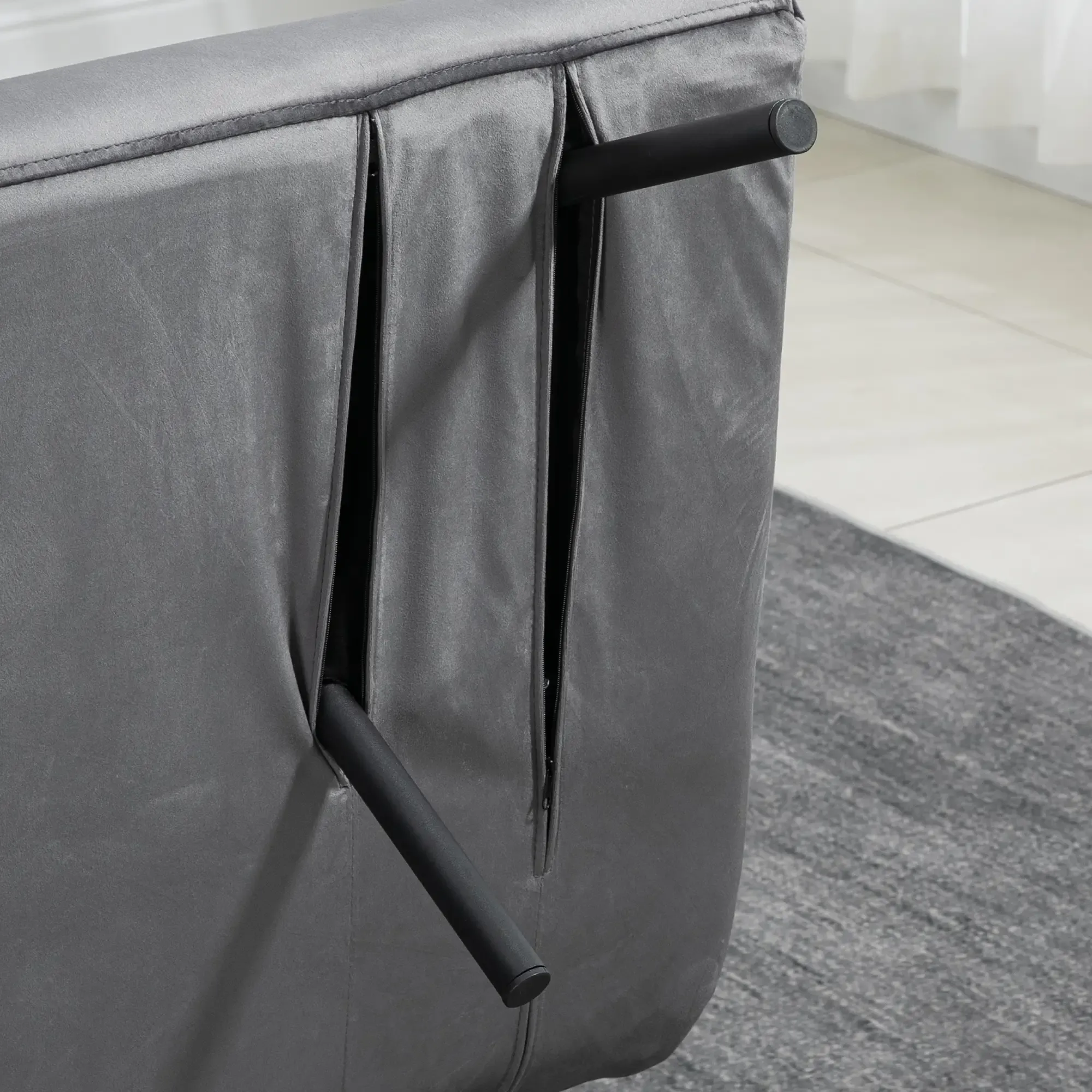 Die Rückseite eines grauen Sofas mit schwarzen Beinen und ein grauer Teppich sind sichtbar.