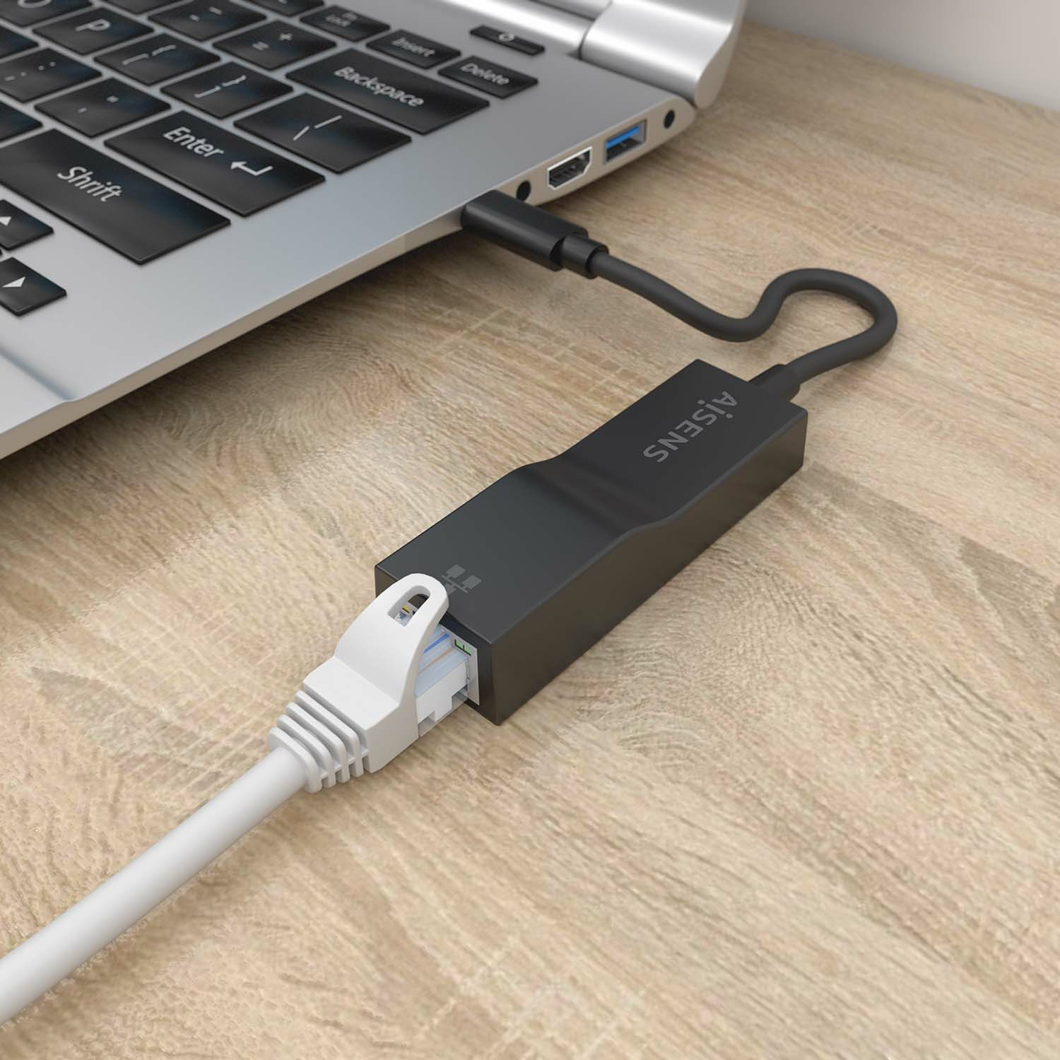 Adaptador USB-C a Ethernet conectado a un portátil. También está conectado el cable Ethernet.