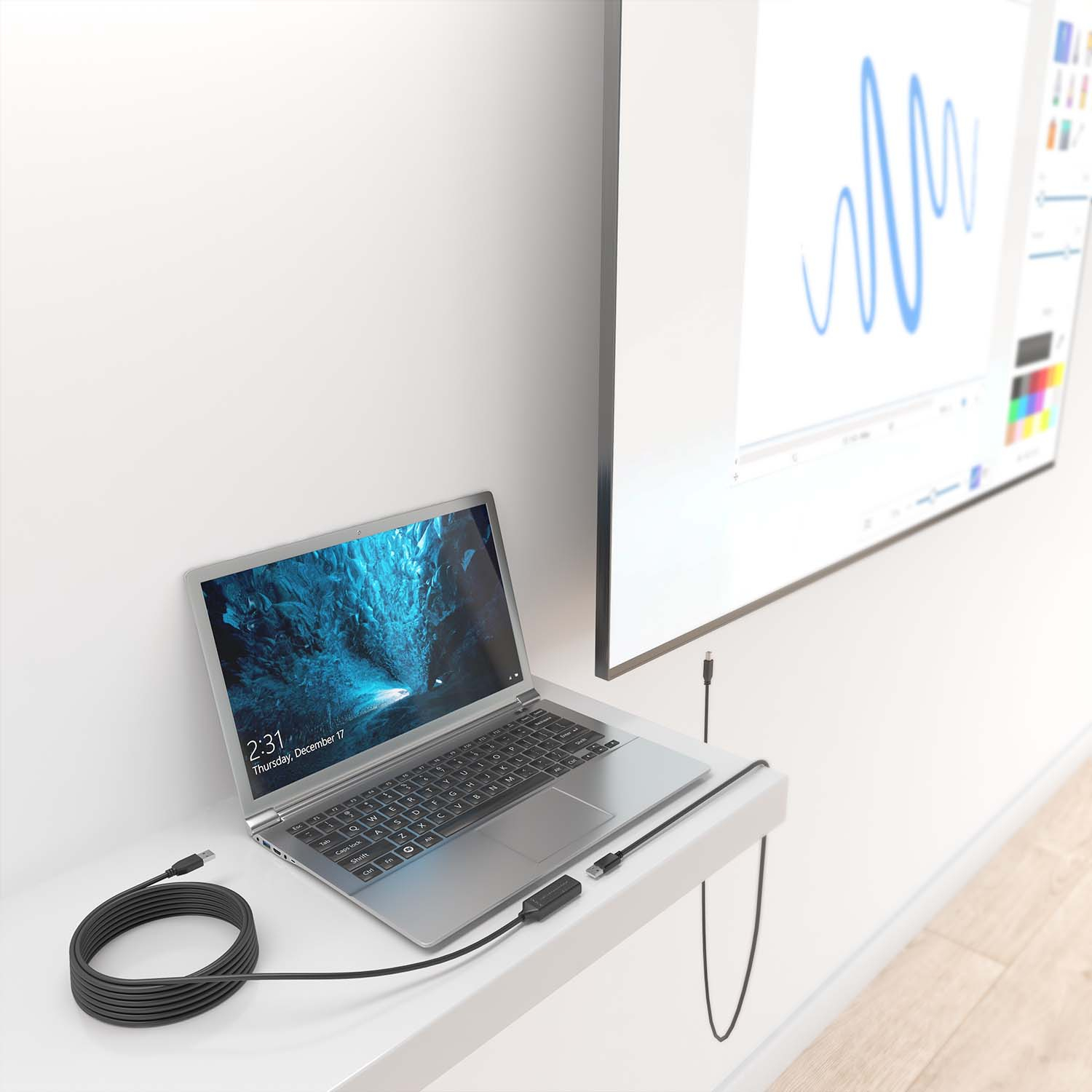 Un portátil está conectado con un adaptador USB-C a una gran pantalla en una pared blanca.