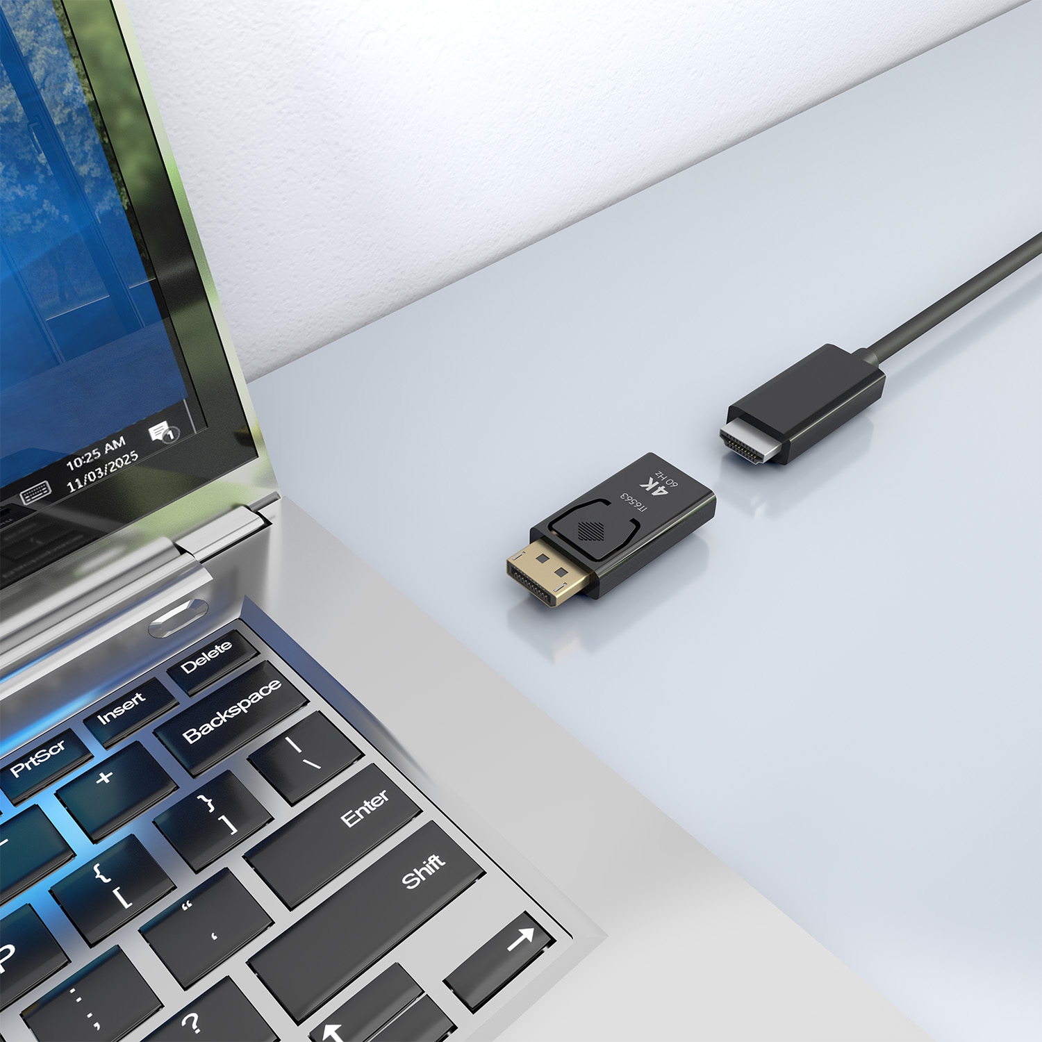 Un portátil está al lado de un adaptador y un cable negros con un conector dorado.