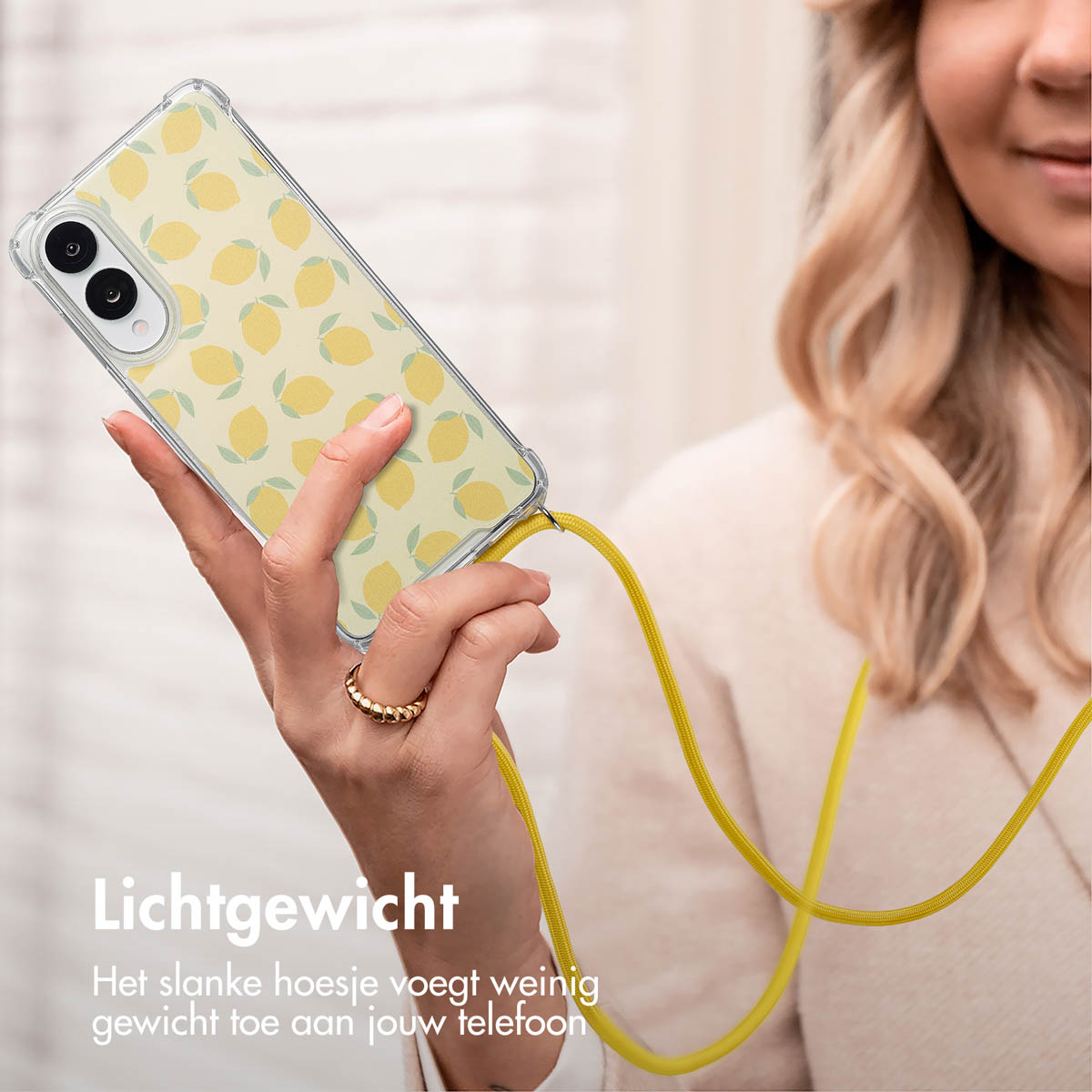 Vrouw die een telefoon vasthoudt met een hoesje met citroenpatroon. De telefoon heeft een gele band. Een ring zit aan haar vinger.