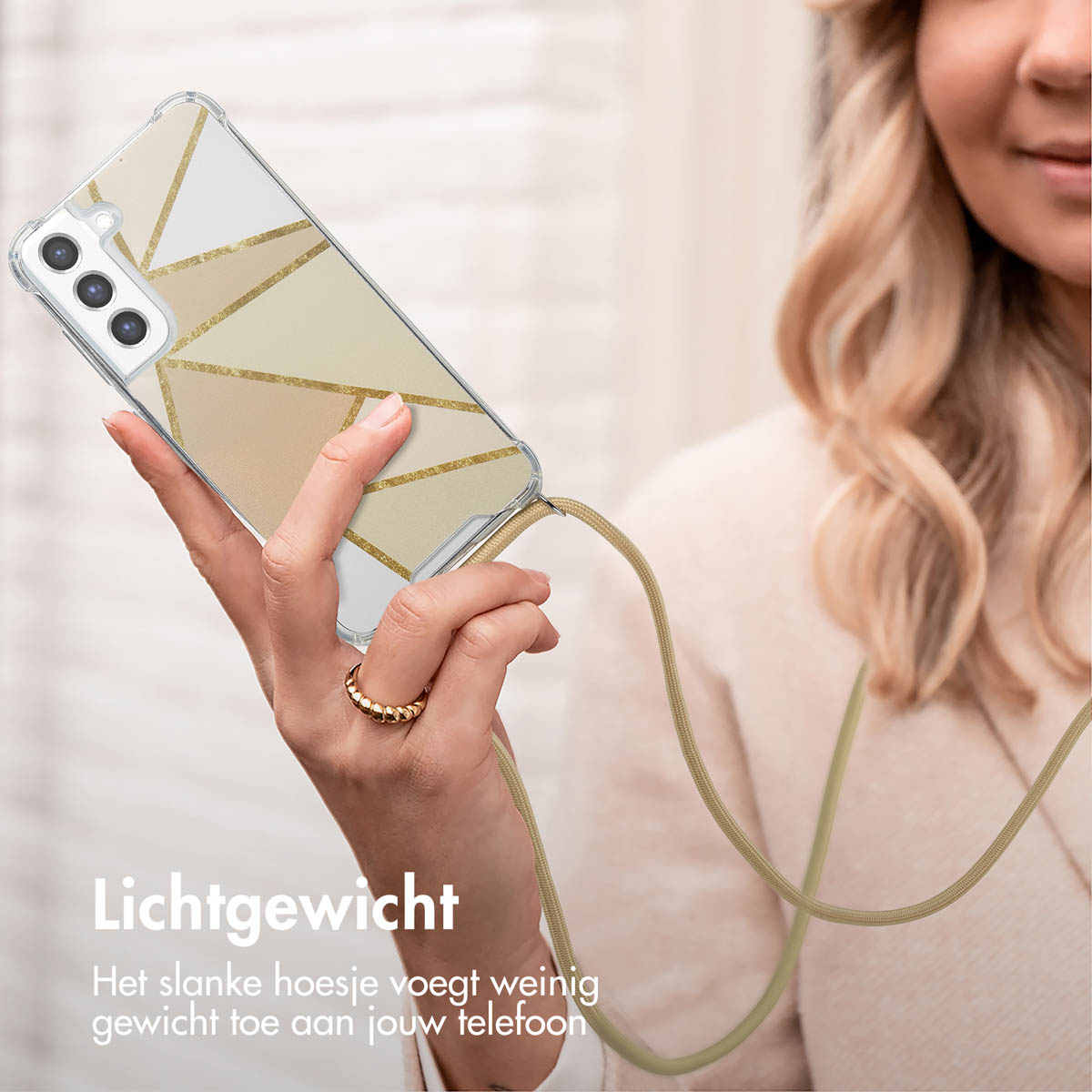 Een vrouw houdt een telefoon vast met een doorzichtige hoes met een goud en wit geometrisch ontwerp.