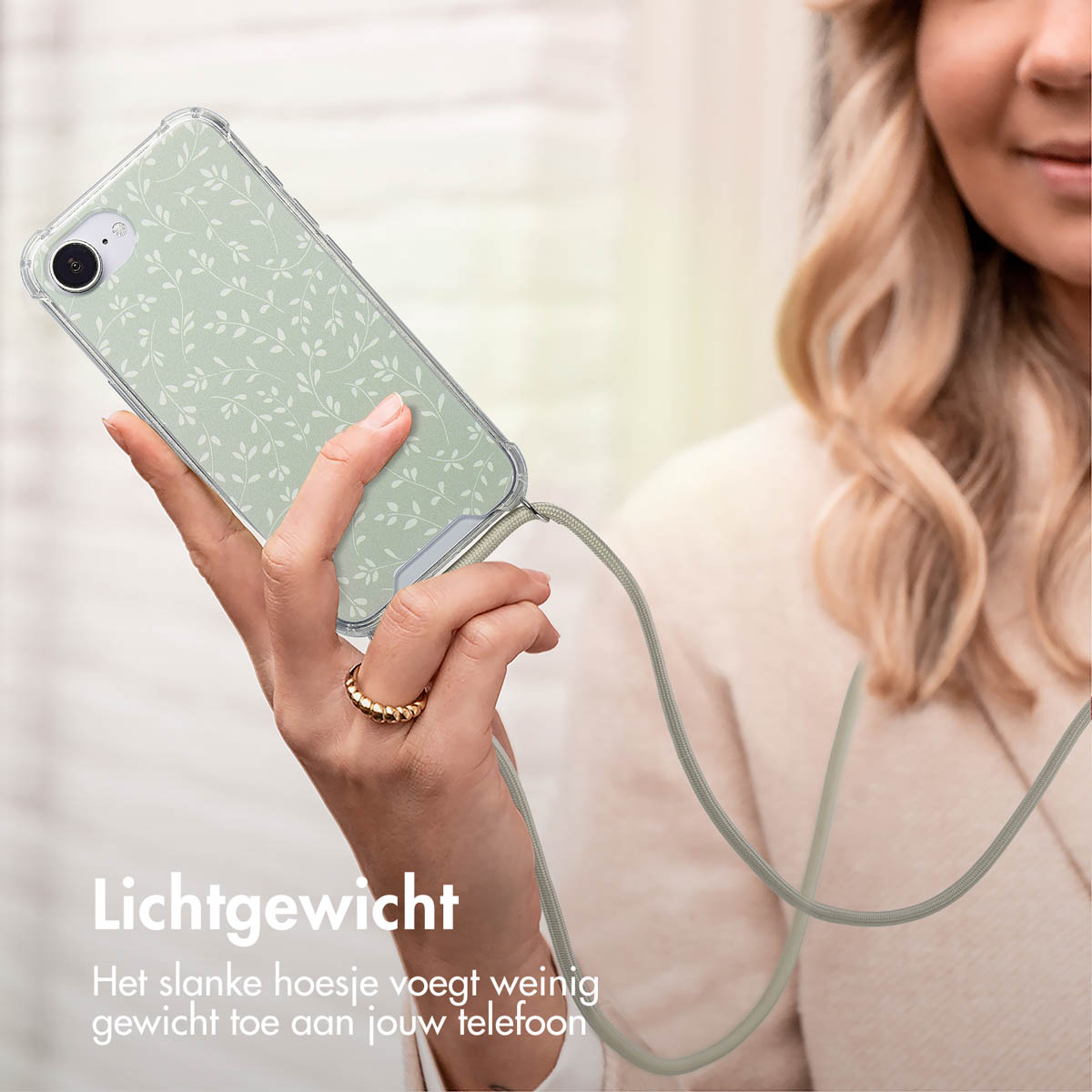 Une femme tient un téléphone dans un étui transparent. L'étui a un motif floral vert. Un cordon est attaché. Texte : Léger.