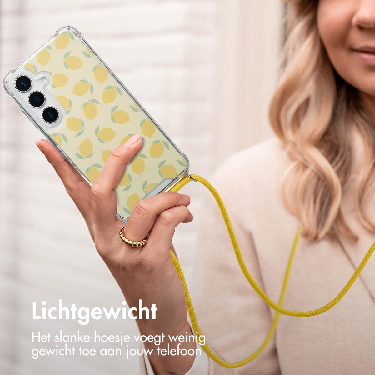 Een vrouw houdt een telefoon vast met een hoesje met citroenpatroon. Een gele lanyard is bevestigd. De telefoon is voor haar.
