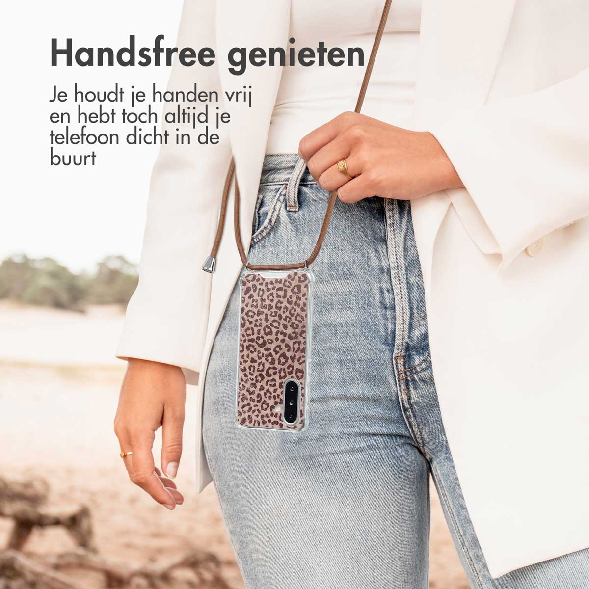 Persoon met witte jas houdt telefoon met luipaardprint hoesje vast. Telefoonriem zichtbaar.