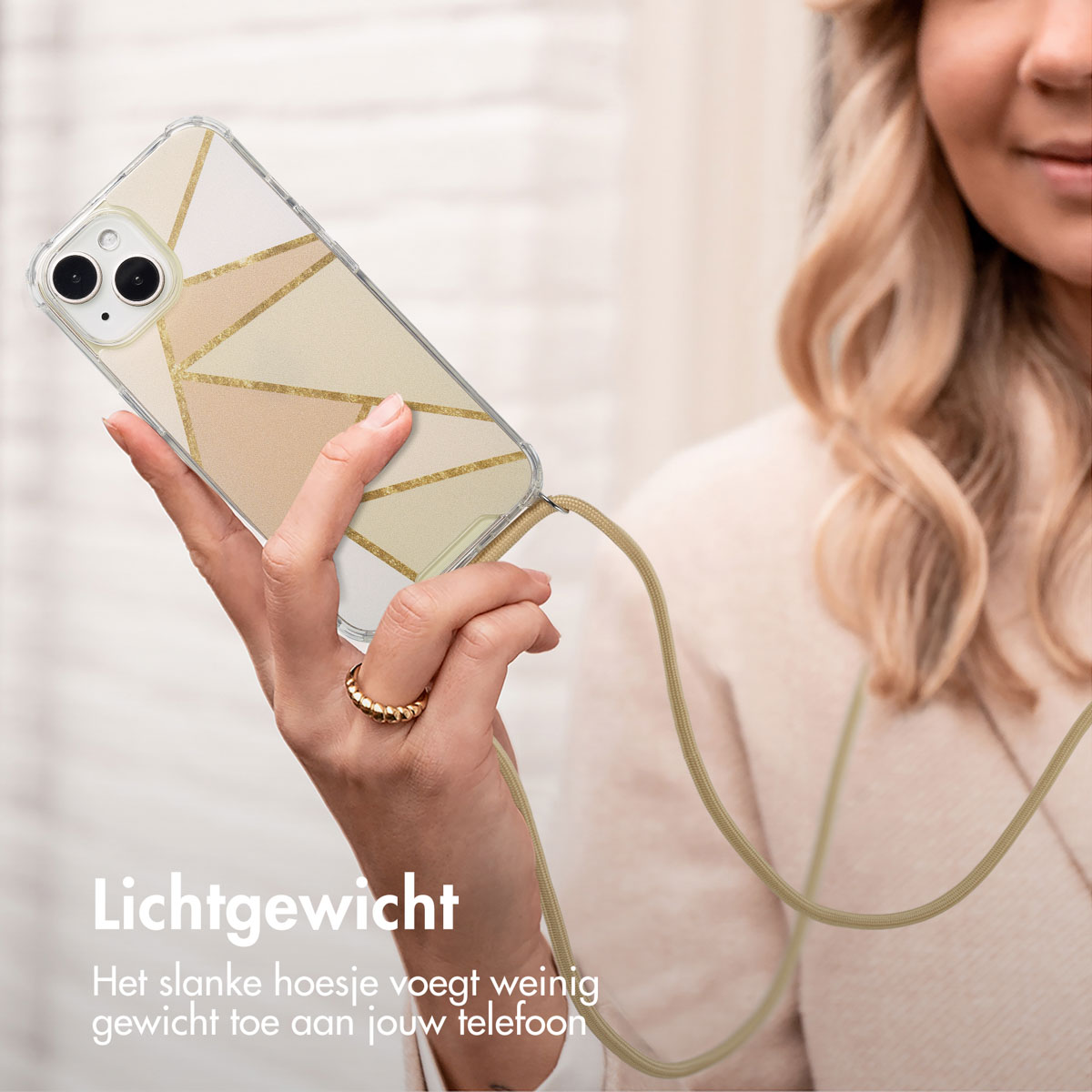 Vrouw houdt telefoon vast met een goud en beige design hoesje en beige lanyard. Tekst: Lichtgewicht. De slanke hoes voegt weinig gewicht toe.