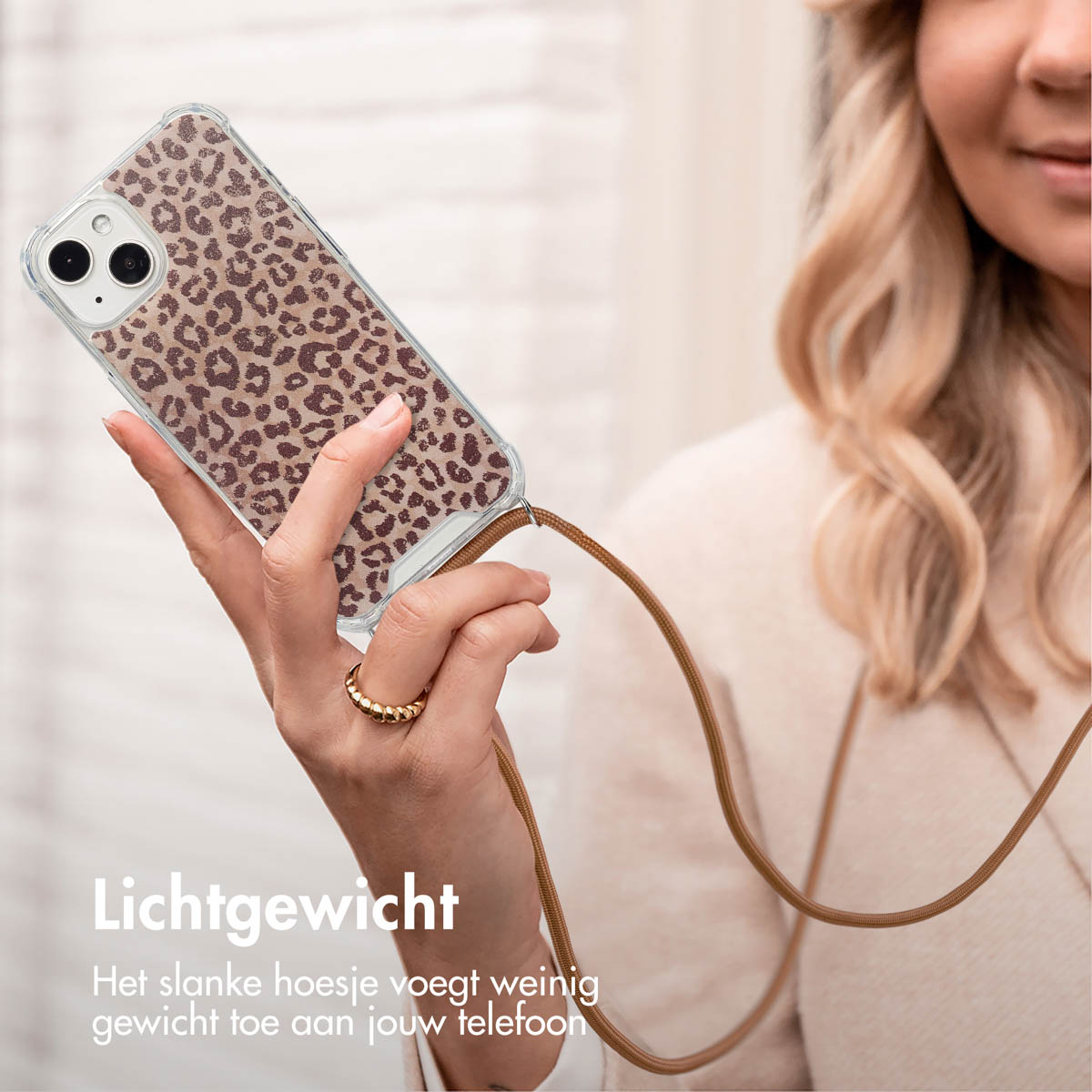 Een vrouw houdt een telefoon vast met een luipaardprint hoesje. De telefoon heeft een bruine band.