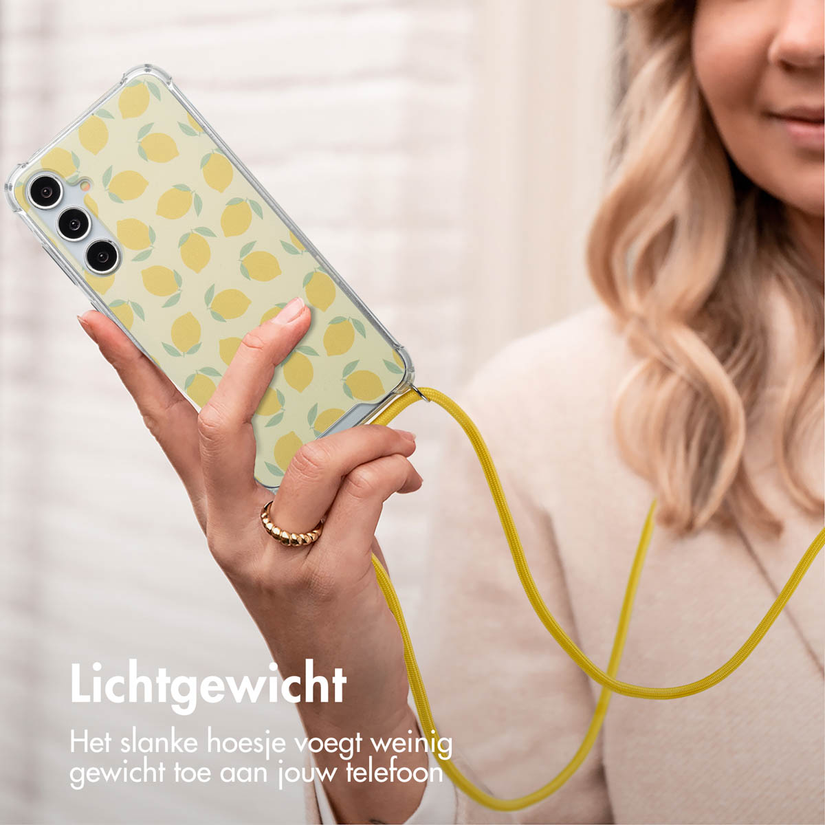 Une femme tient un téléphone avec un étui à motif de citron. Le téléphone a une sangle jaune.