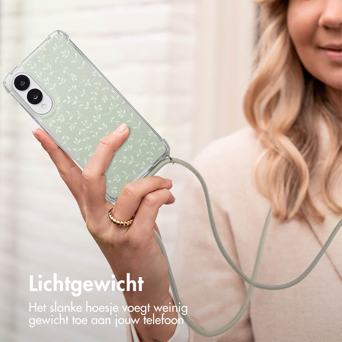 Una donna che tiene un telefono con una custodia verde con foglie bianche. Il telefono ha un cordino verde. Testo: Leggero.