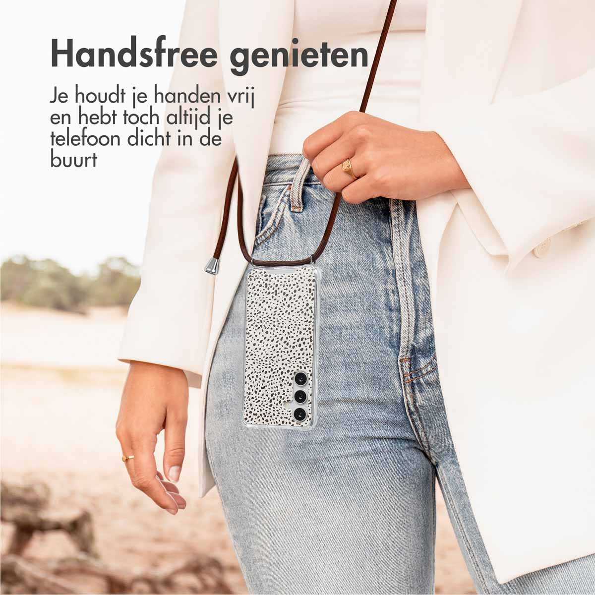 Femme avec une coque de téléphone à motif dalmatien, portant une veste blanche, debout en extérieur avec un jean.