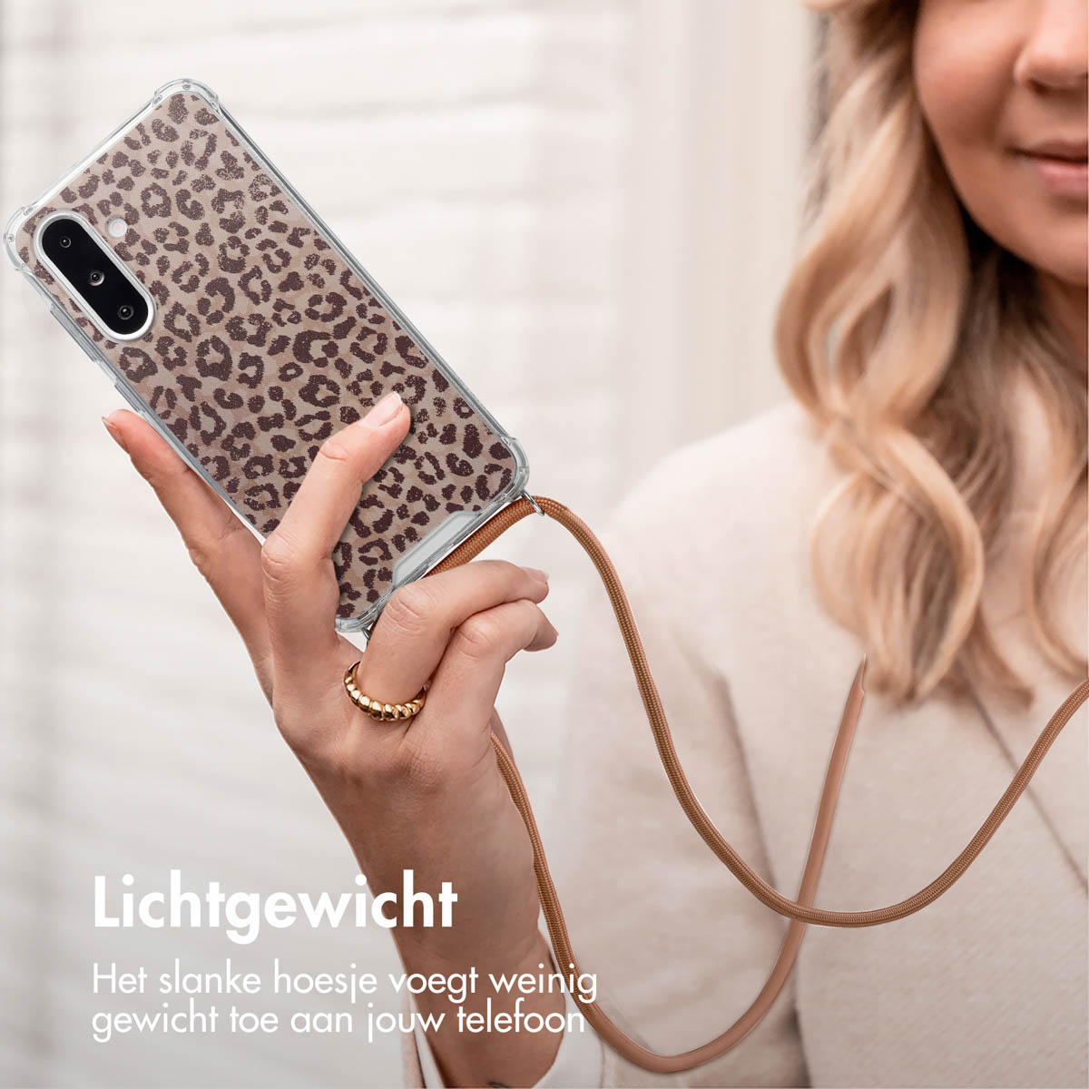 Vrouw houdt telefoon vast met luipaardprint hoesje en bruine band.