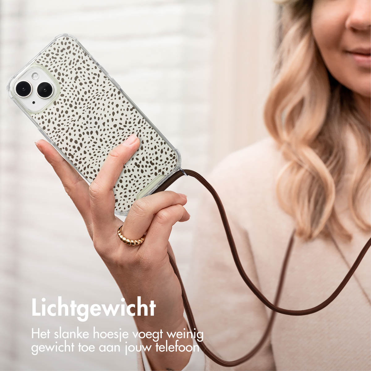 Vrouw die een telefoon vasthoudt in een hoesje met een bandje, met een patroon.