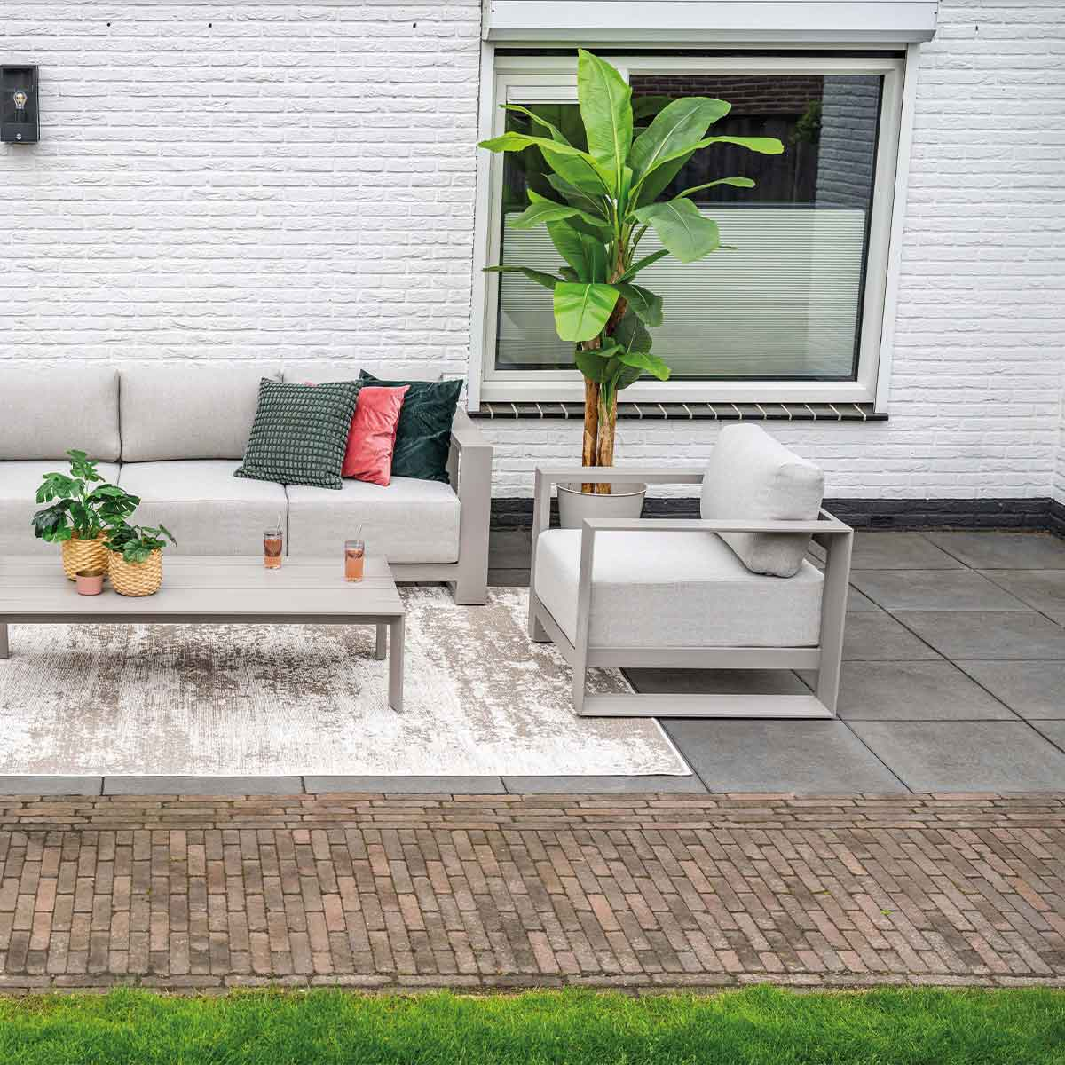 Outdoor patio setting with furniture, plants, and brickwork, creating a relaxed ambiance.