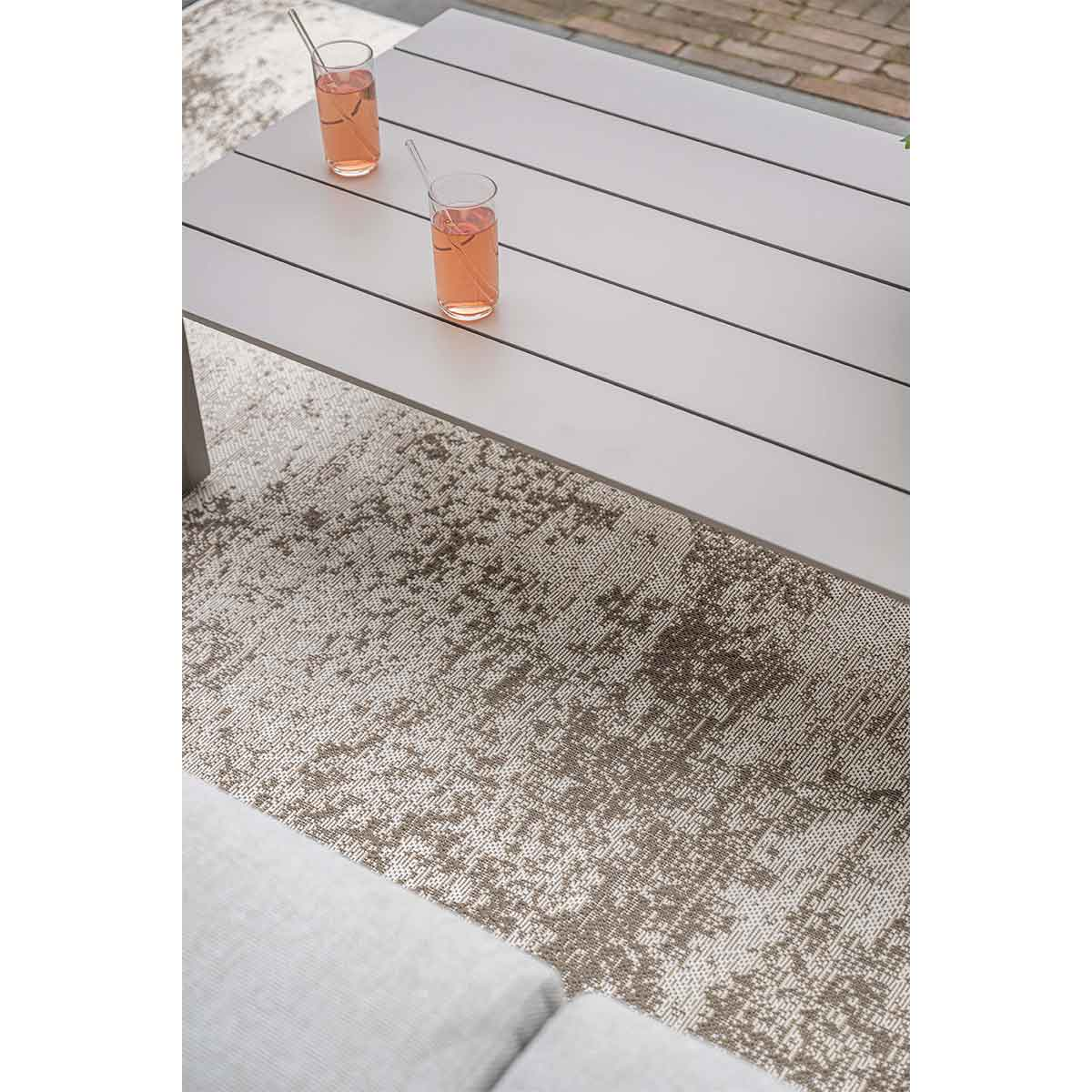 Overhead view of a table and rug. Two glasses of pink drink sit on the table.