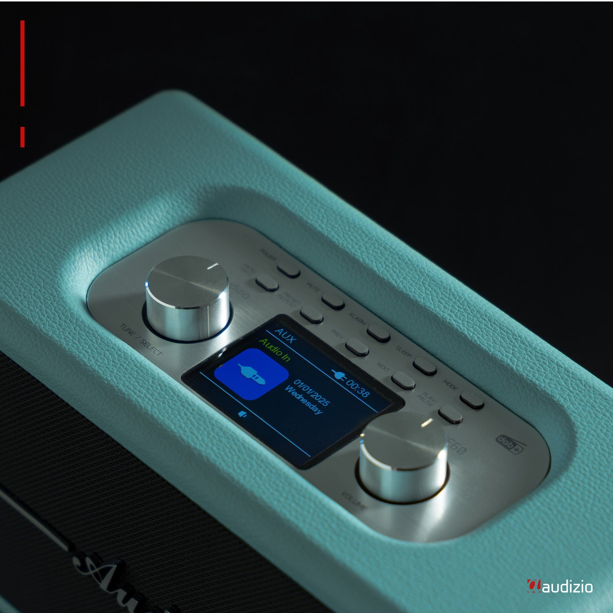 Primer plano de radio azul claro con pantalla negra. Perillas plateadas. 'Audizio' abajo.