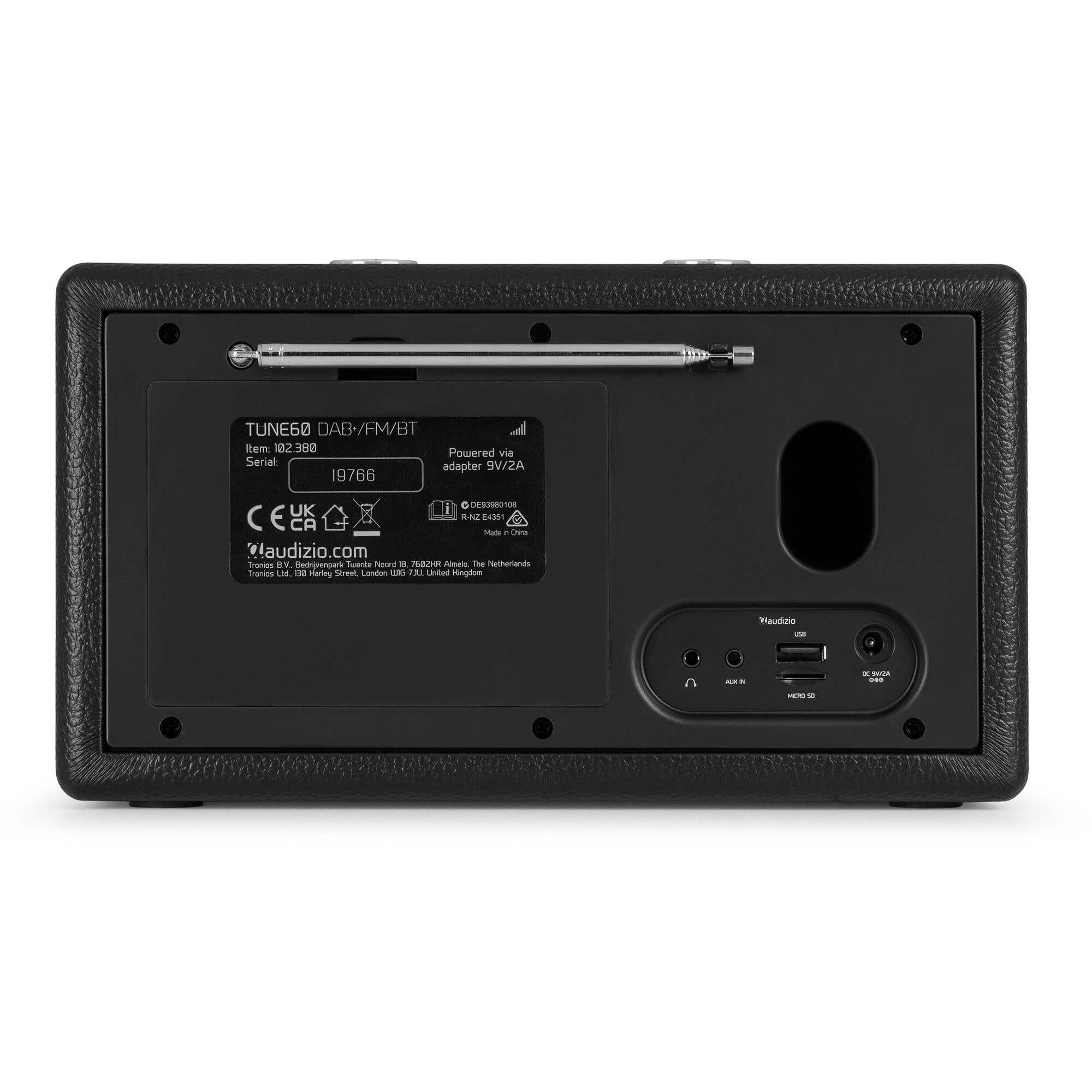 Parte trasera de una radio negra con varias etiquetas y antena. Puertos para aux in y USB.