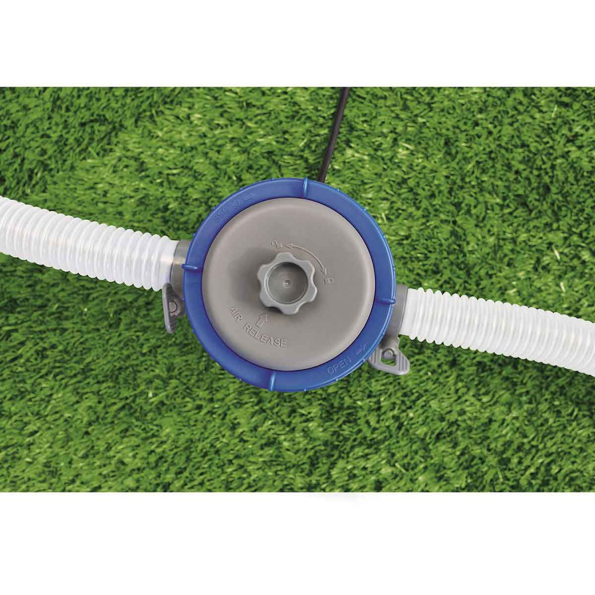 Een blauw en grijs apparaat met witte buizen en een centrale bediening, op een groene grasmat.