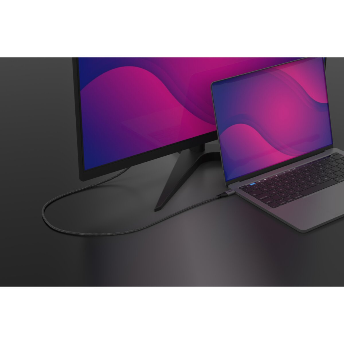 Un monitor è collegato a un laptop con un cavo. Lo sfondo è una superficie scura.