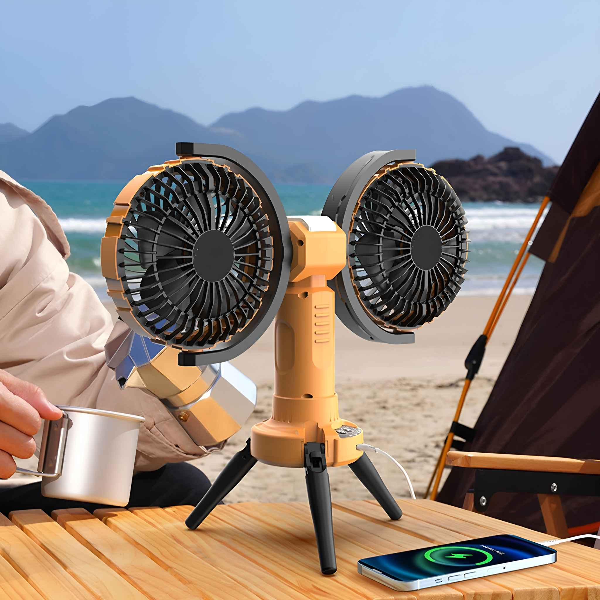 Ein tragbarer Ventilator auf einem Stativ auf einem Holztisch, eine Person, ein Telefon und ein Zelt im Hintergrund.