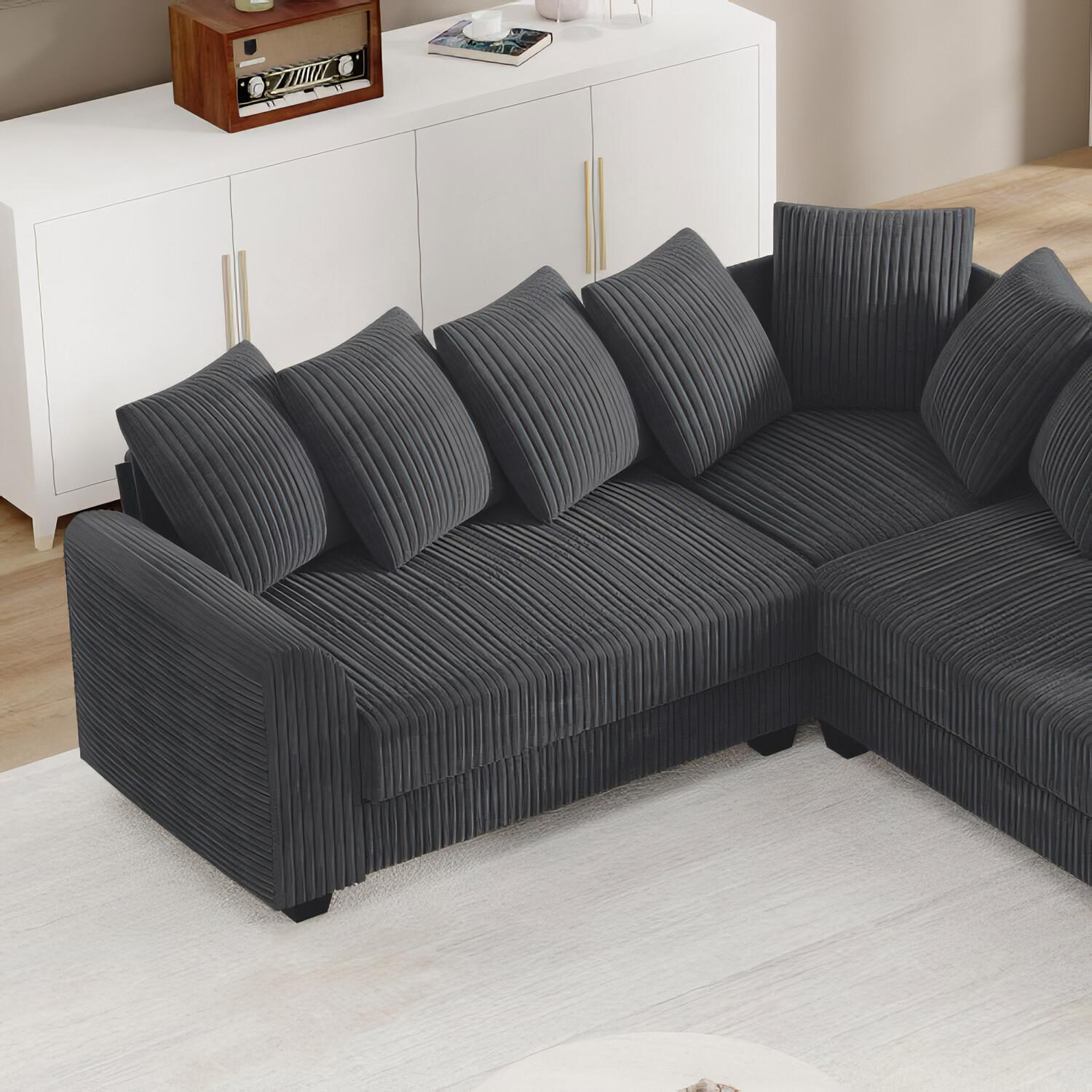 Ein dunkelgraues Ecksofa mit mehreren Kissen in einem Wohnzimmer.