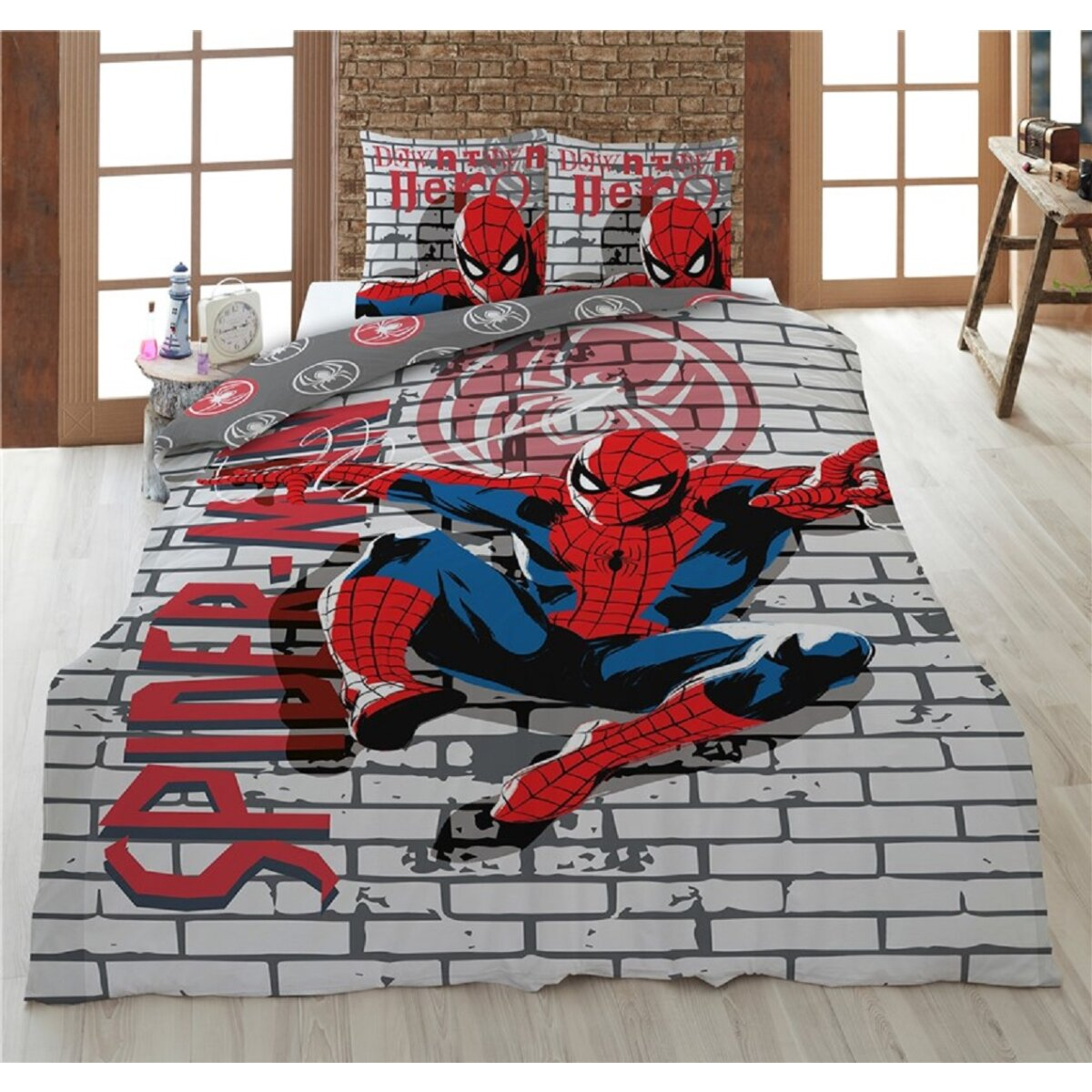 Spiderman en una cama con fondo de pared de ladrillo y dos fundas de almohada con la cabeza de Spiderman.