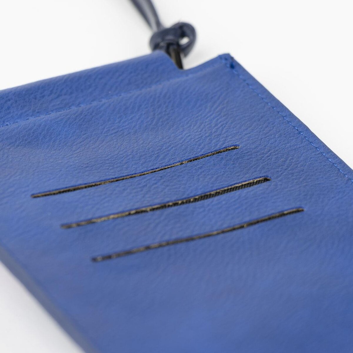 Close-up van een blauwe telefoonhouder met drie horizontale sleuven en een riem.