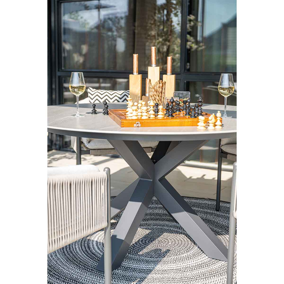 Chessboard on a table with wine glasses and outdoor setting.