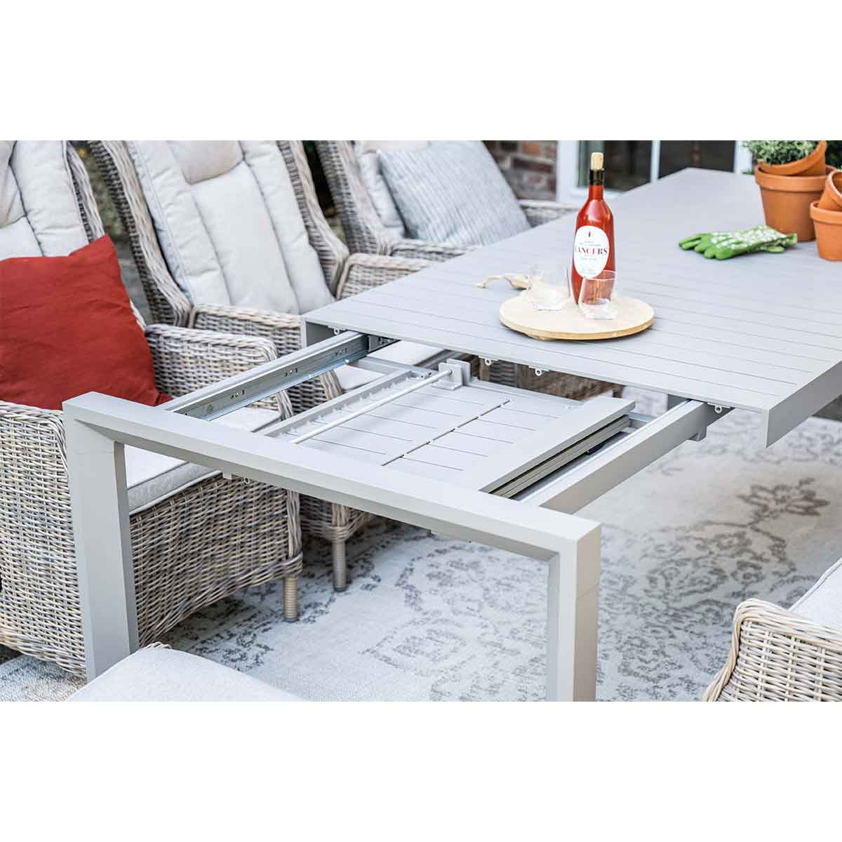 Extendable outdoor table with wine and glasses on top, showing the extension mechanism.