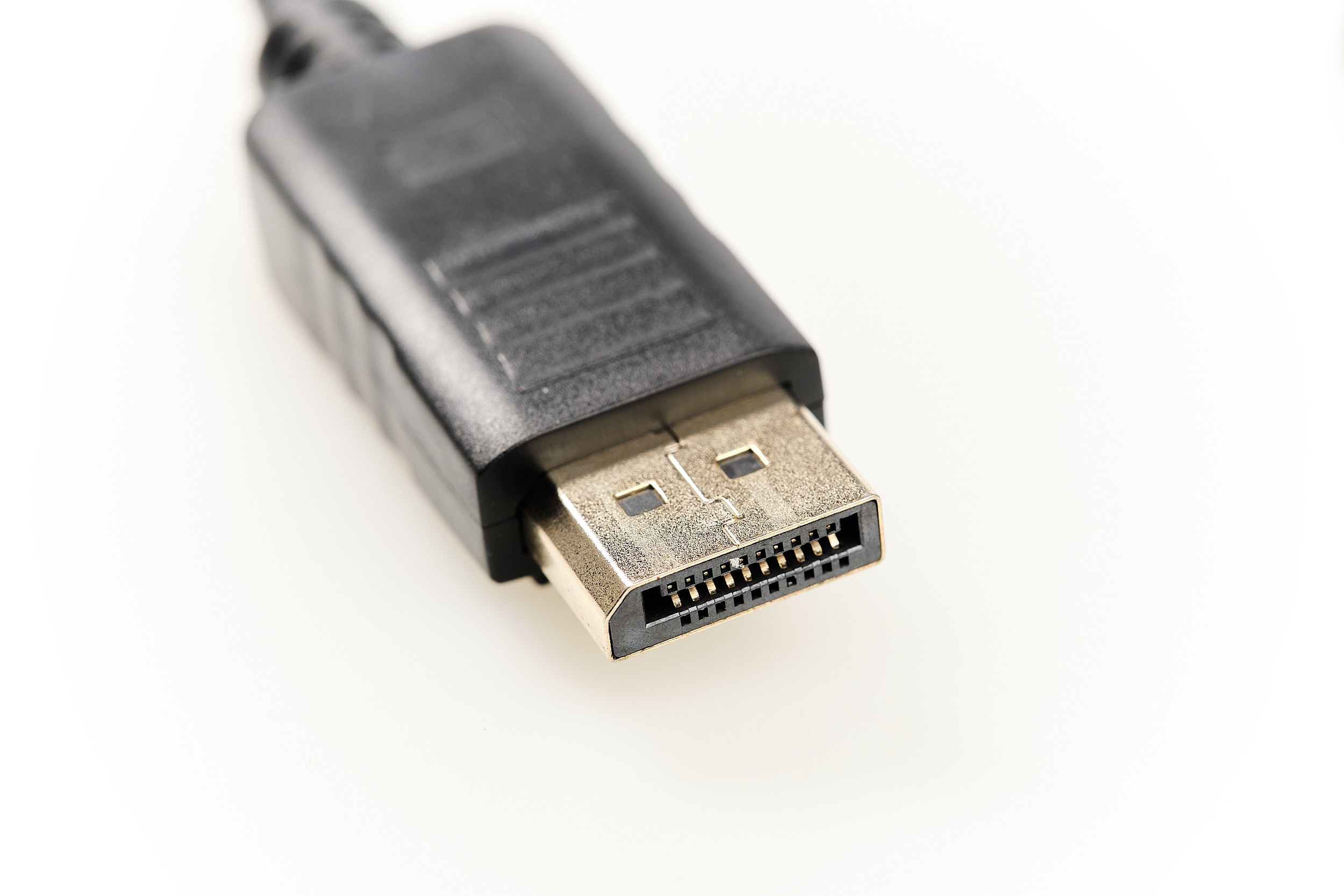 Primer plano de un conector DisplayPort, plástico negro, con pines dorados, sobre un fondo blanco.