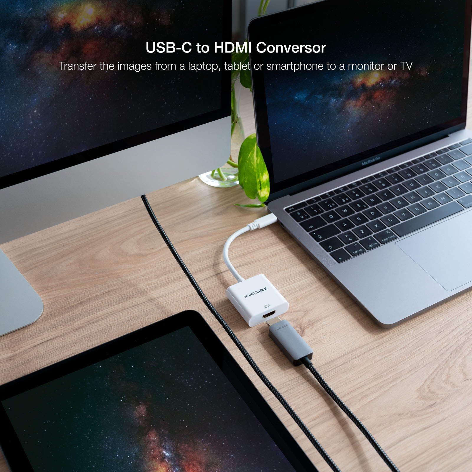 Adaptador USB-C a HDMI con configuración de portátil, tableta y monitor en un escritorio de madera.
