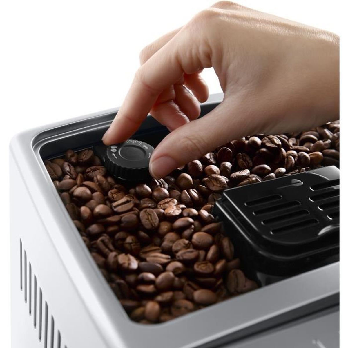 Die Hand einer Person stellt den Bohnenauswahlschalter an einer Kaffeemaschine ein. Kaffeebohnen sind sichtbar.
