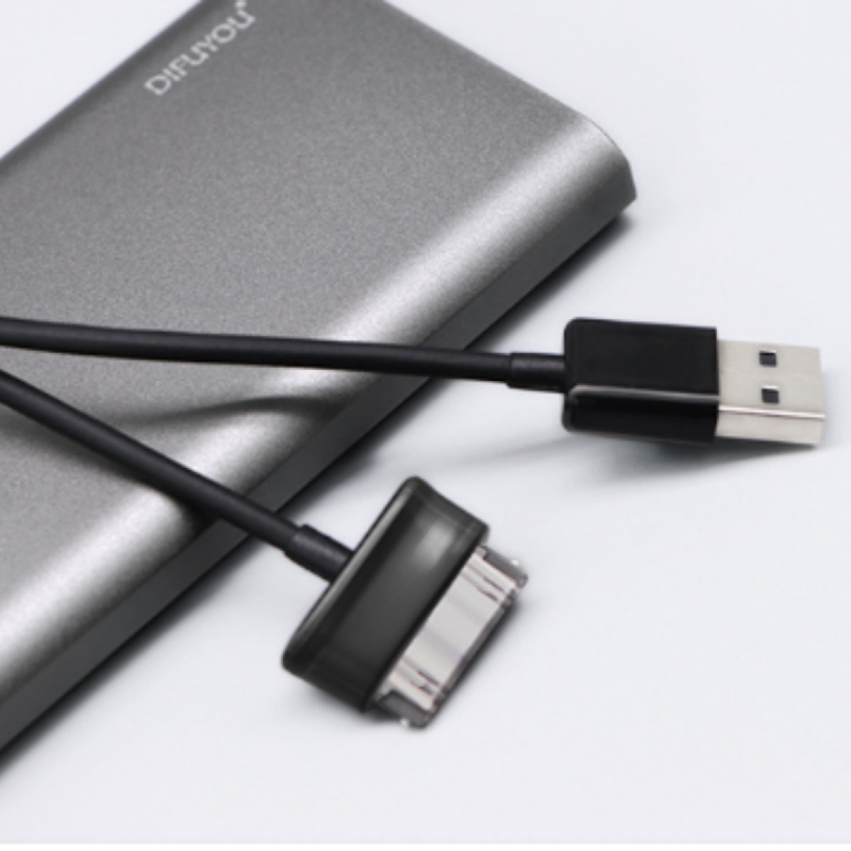 Szary power bank i dwa czarne kable do ładowania, jeden ze złączem USB i jeden ze złączem Apple.