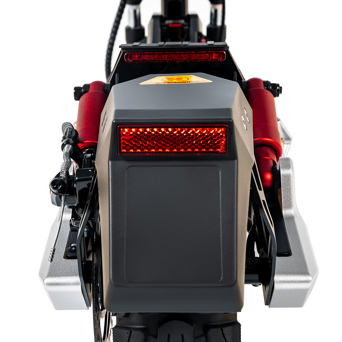 Zbliżenie na tył hulajnogi elektrycznej z czerwonymi amortyzatorami. Tło jest białe.